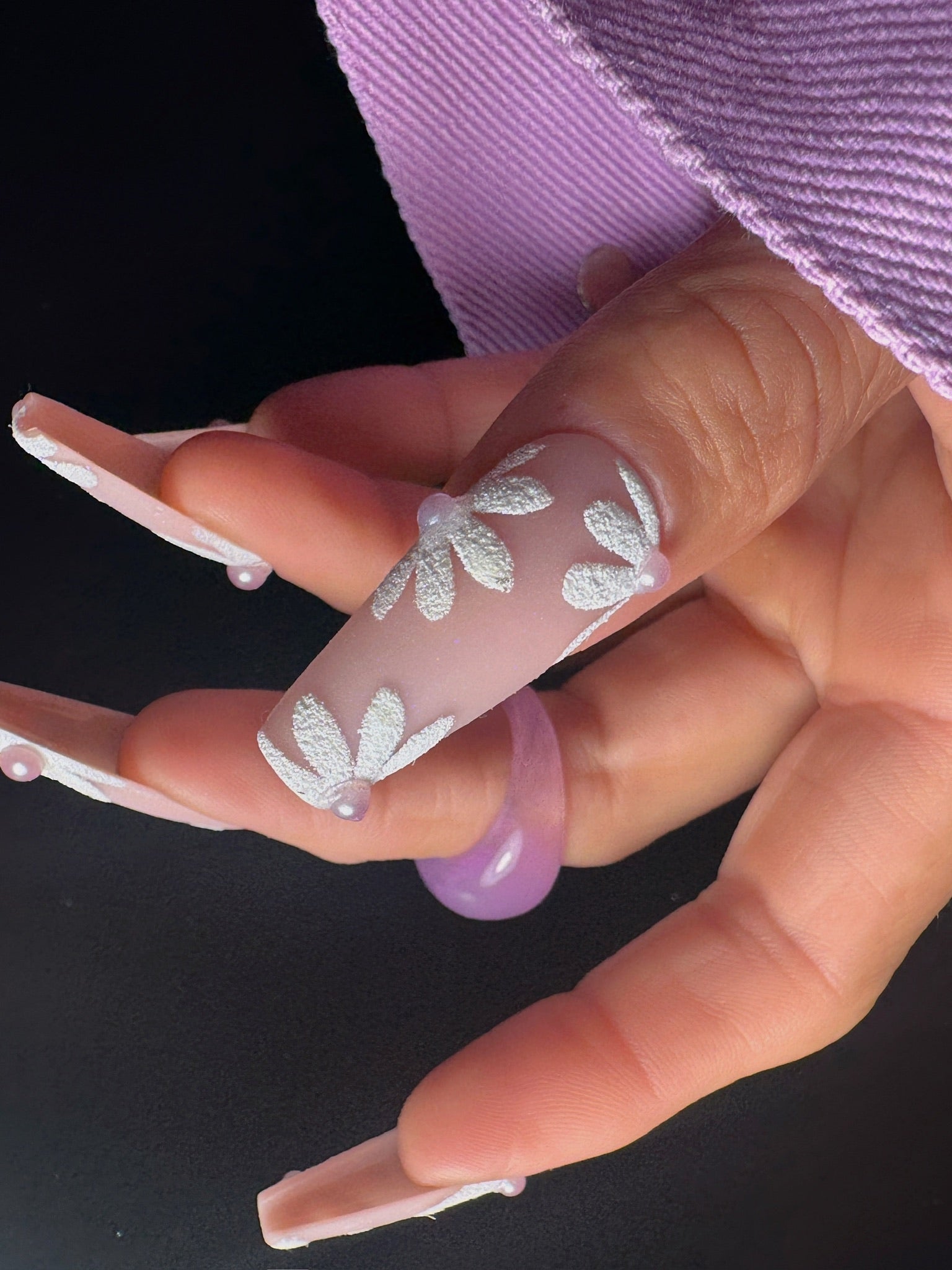 Close-up of a hand with decorative nail art on a black background