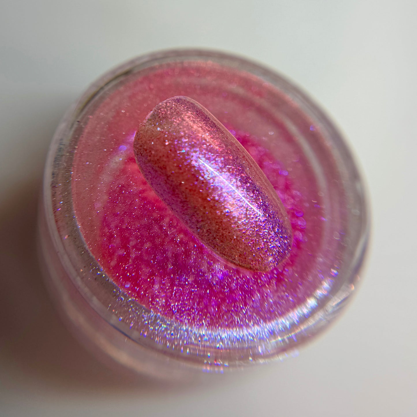 close up of iridescent colored bail tip resting on transparent jar on blurred background