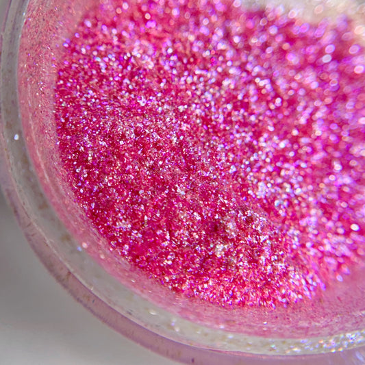 Close up vide of pink fine glitter in transparent jar on light background