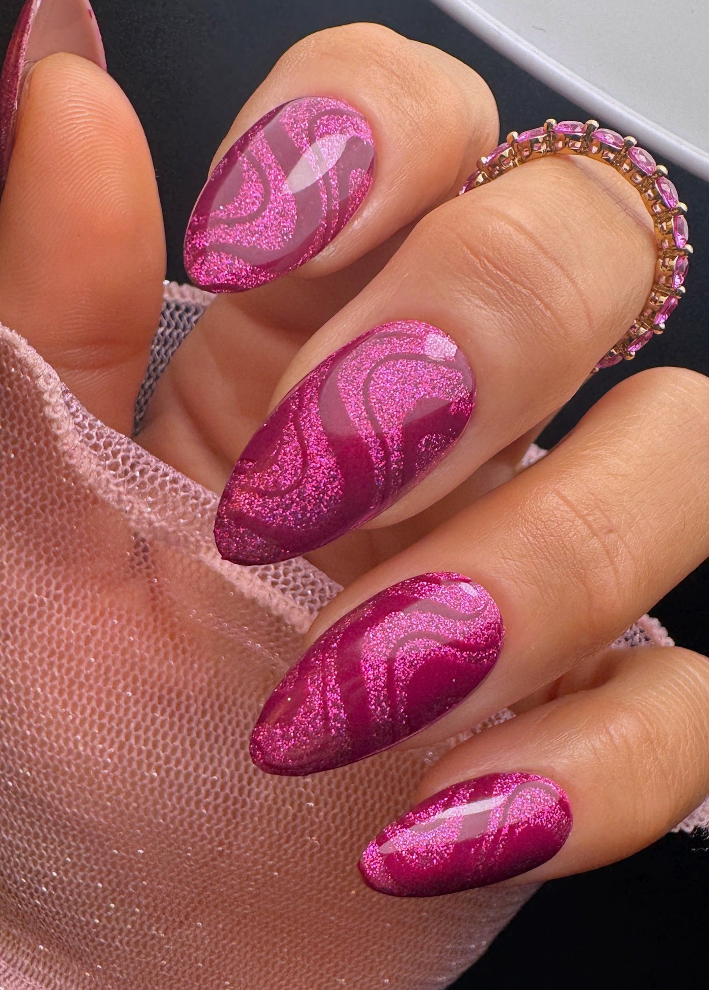 Close-up of a hand with pink marbled nail design.