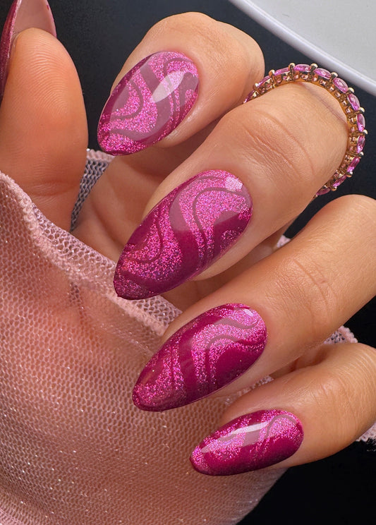 Close-up of a hand with pink marbled nail design.