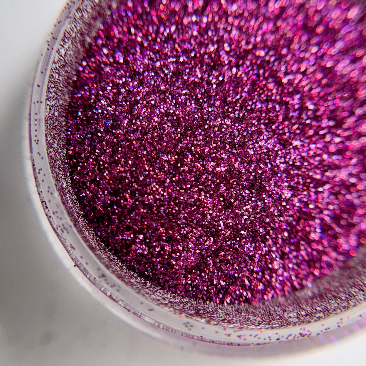Close up of fine glitter particles in jar on blurred background.