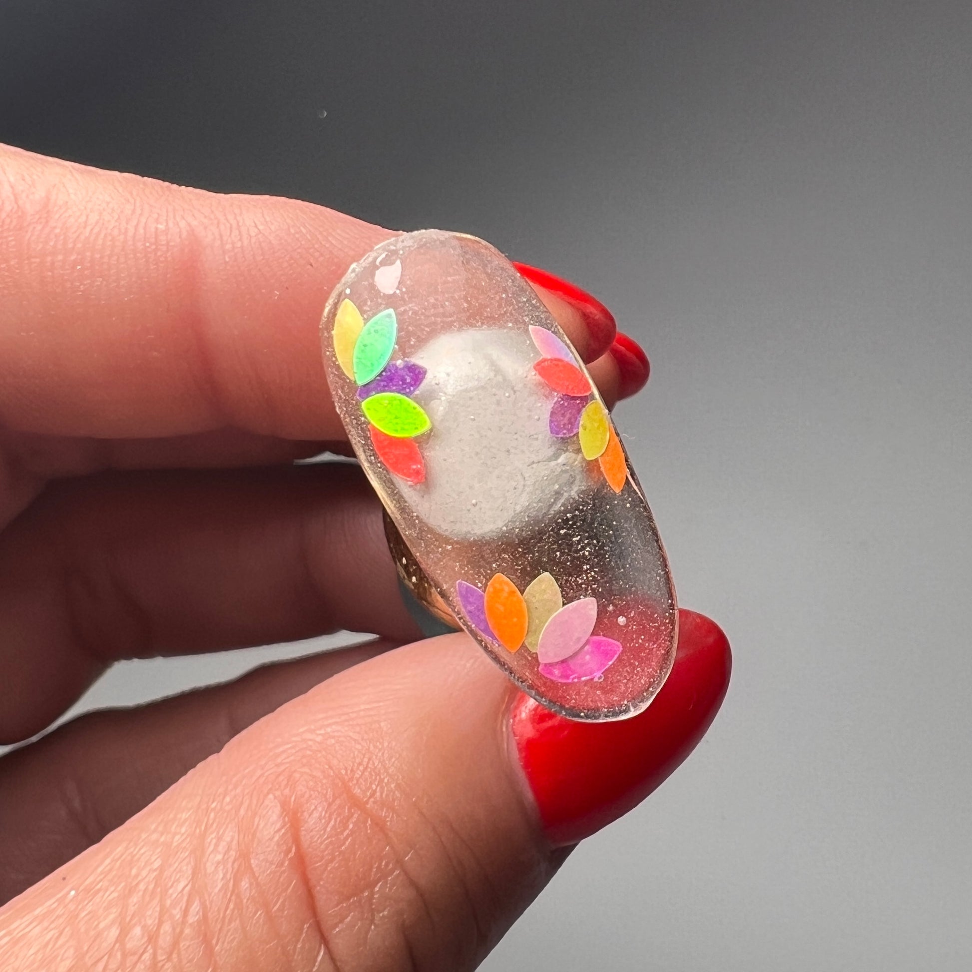 Still of hand holding decorated nail tip. 