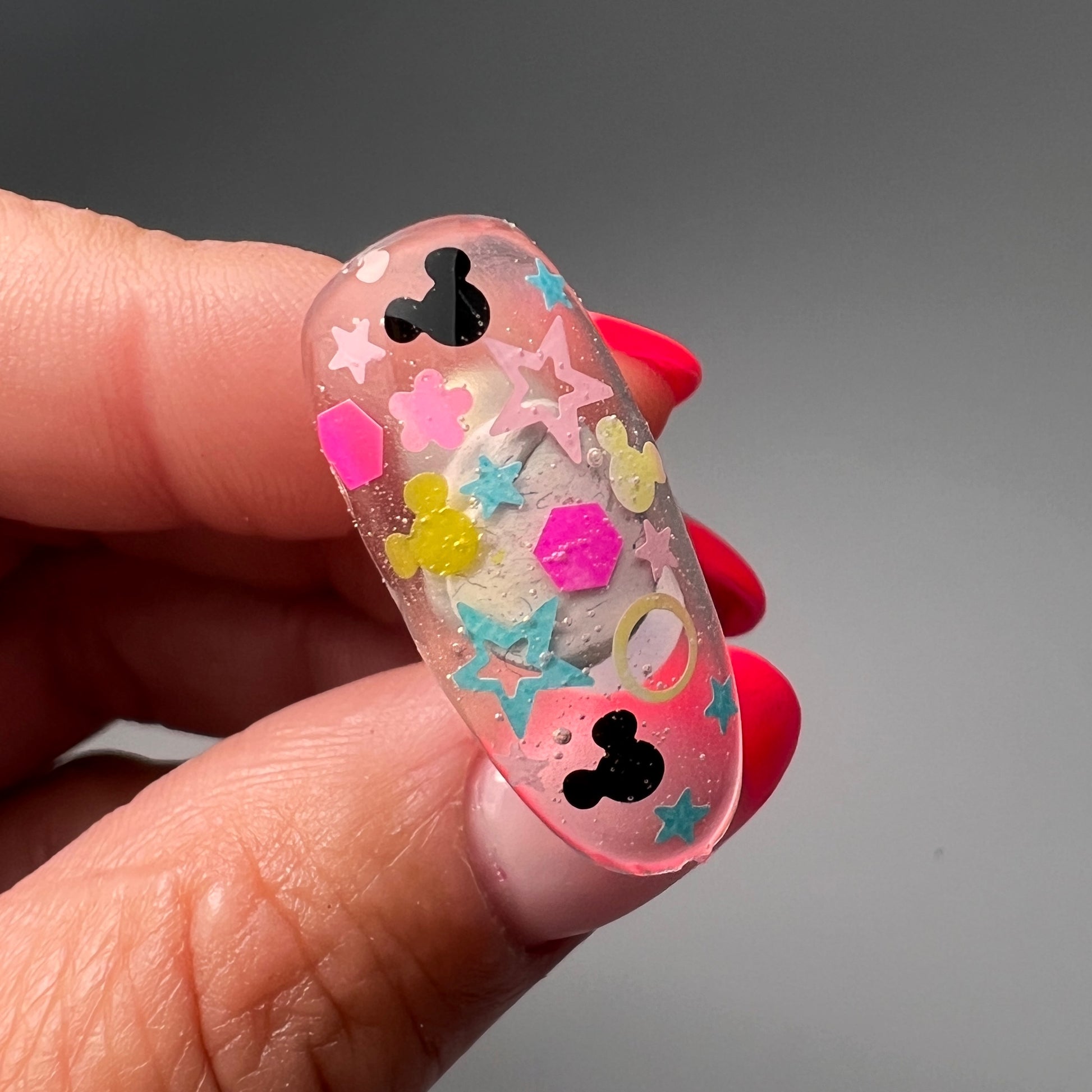 Still of hand holding decorated nail tip. 
