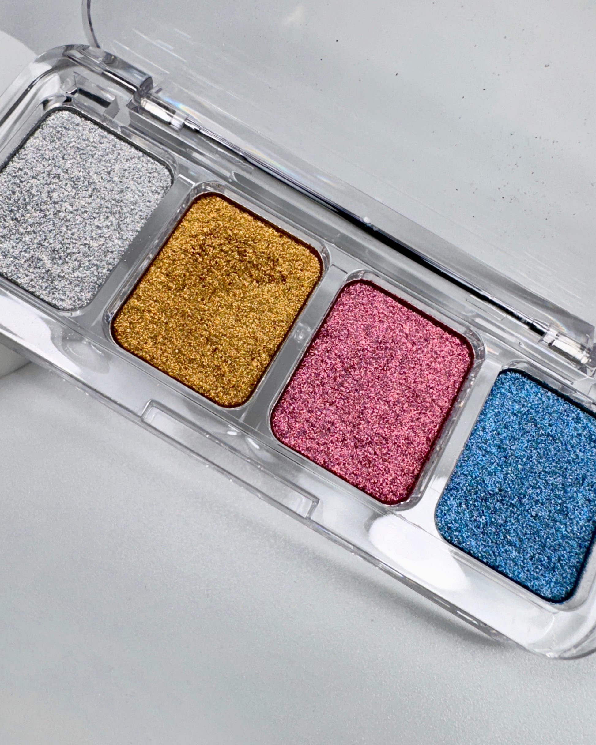Chrome palette with glittery pigment in silver, gold, pink, and blue on a light gray background.