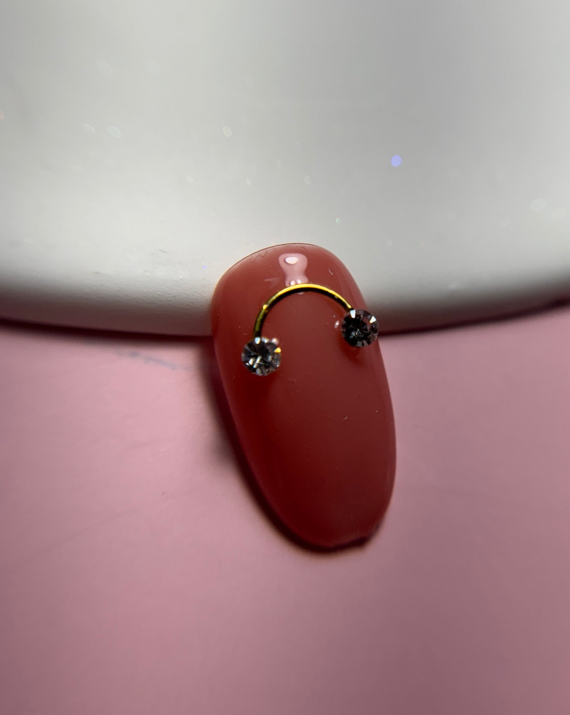 Close up of decorated nail tip on white plate and pink surface