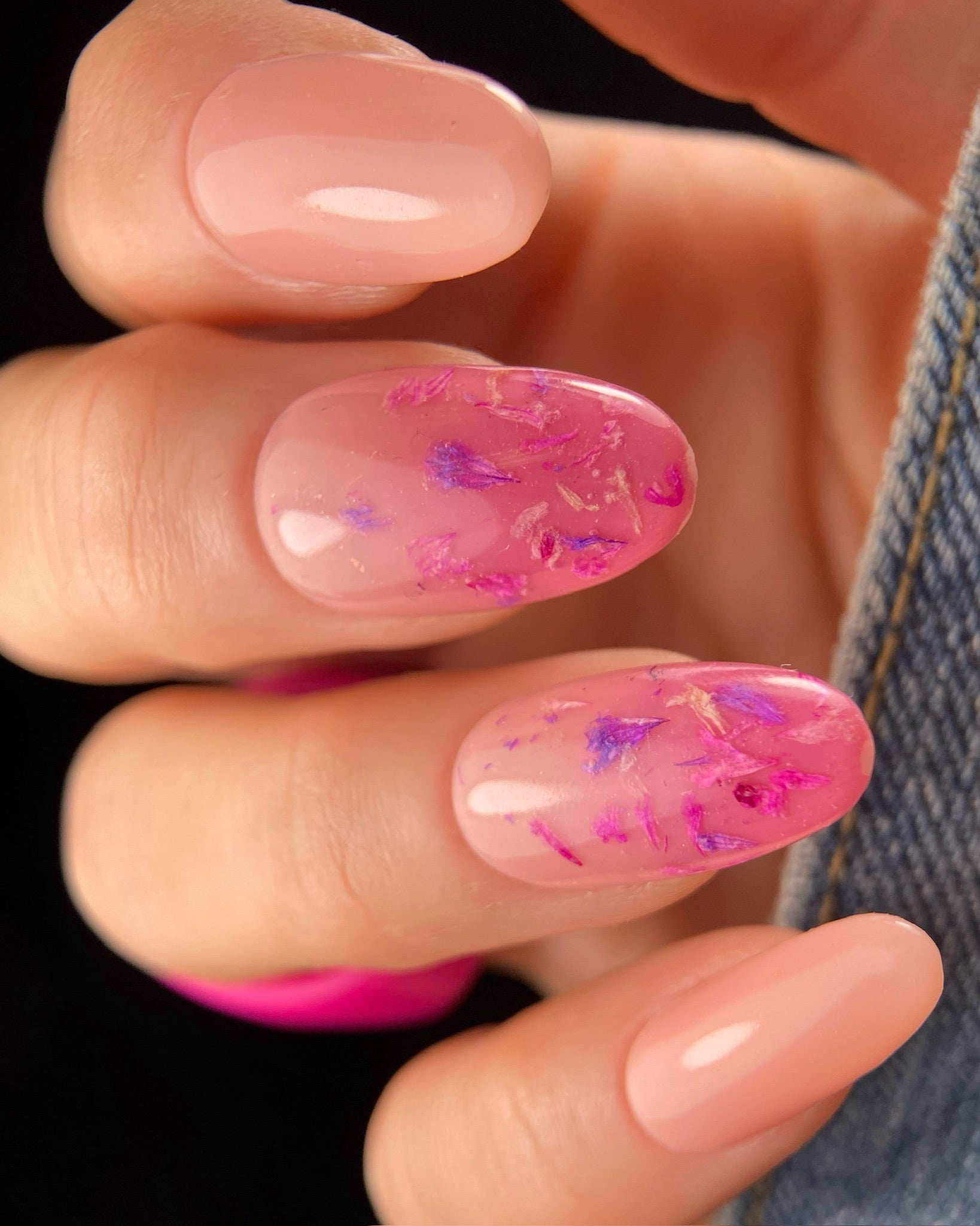 Close-up of a hand with pink floral nail design on a dark background