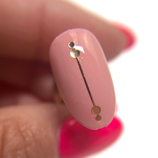 Hand holding decorated nail tip on blurred background.