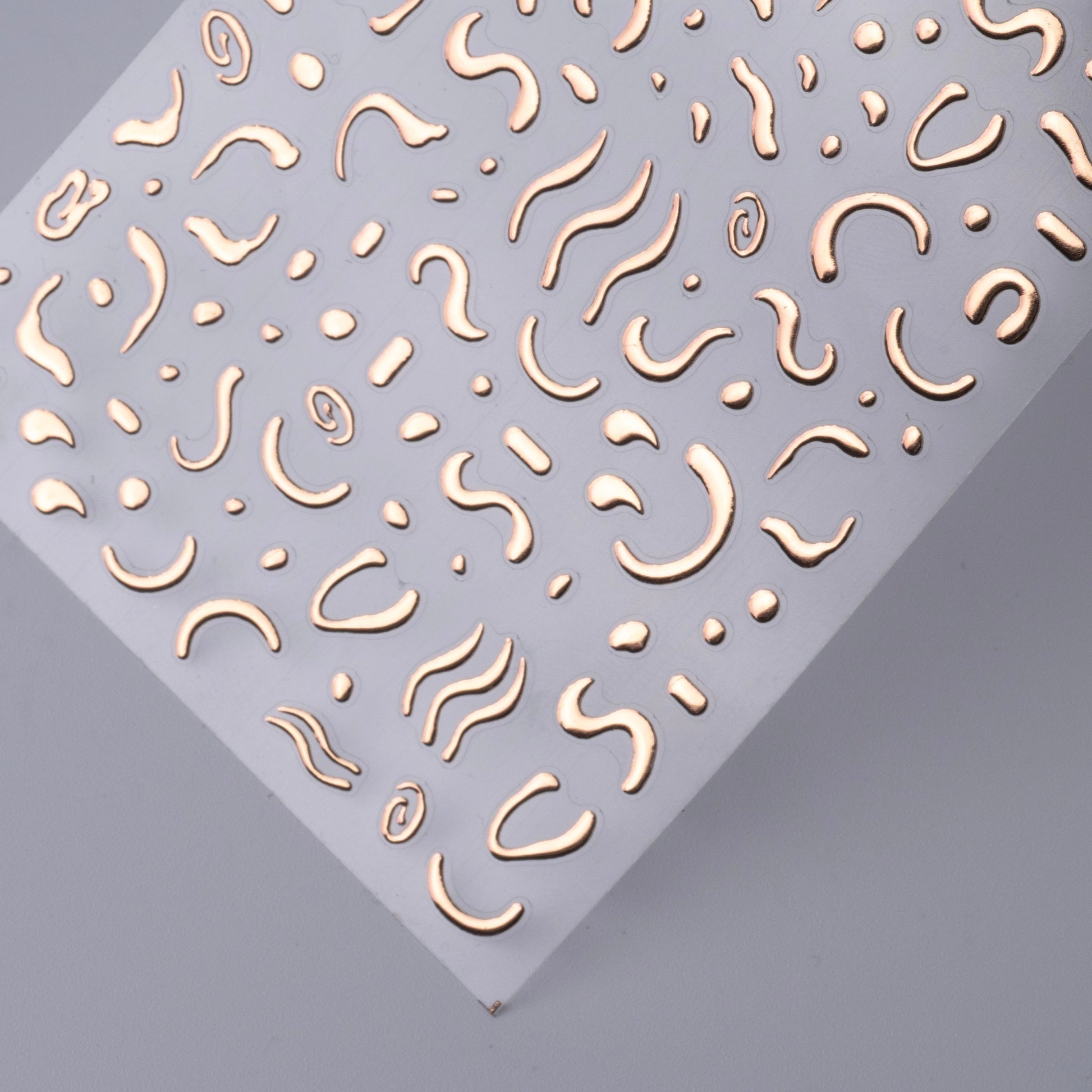 Nail decal sheet with wavy metallic patterns on a gray background