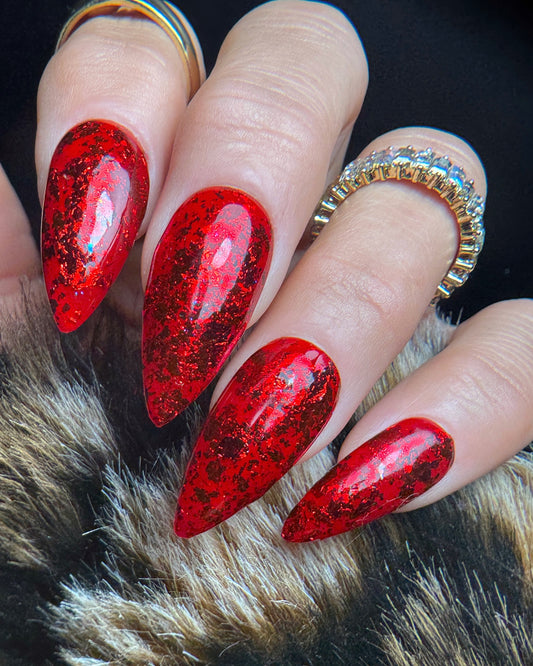Red glittery nails on a hand with a fur background