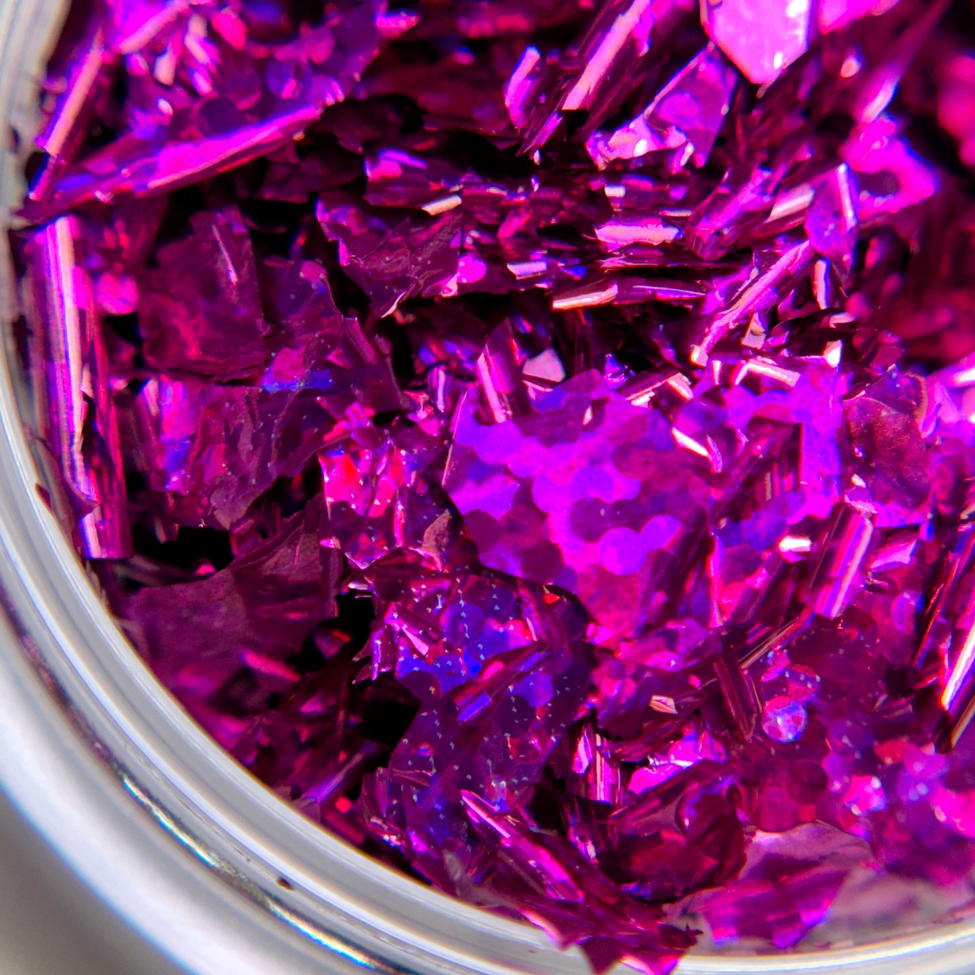 A close-up image of magenta-colored glitter flakes, intended for nail art.
