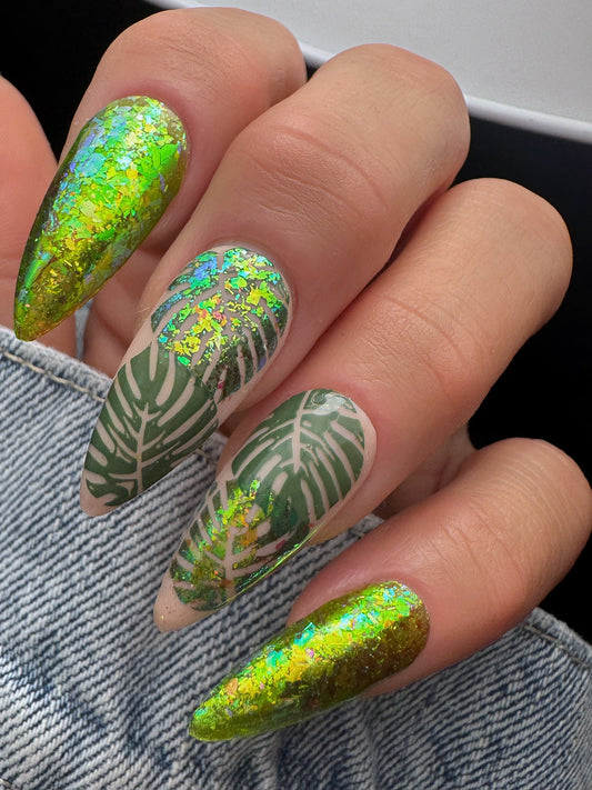 Nails with green and gold leaf design on a denim background