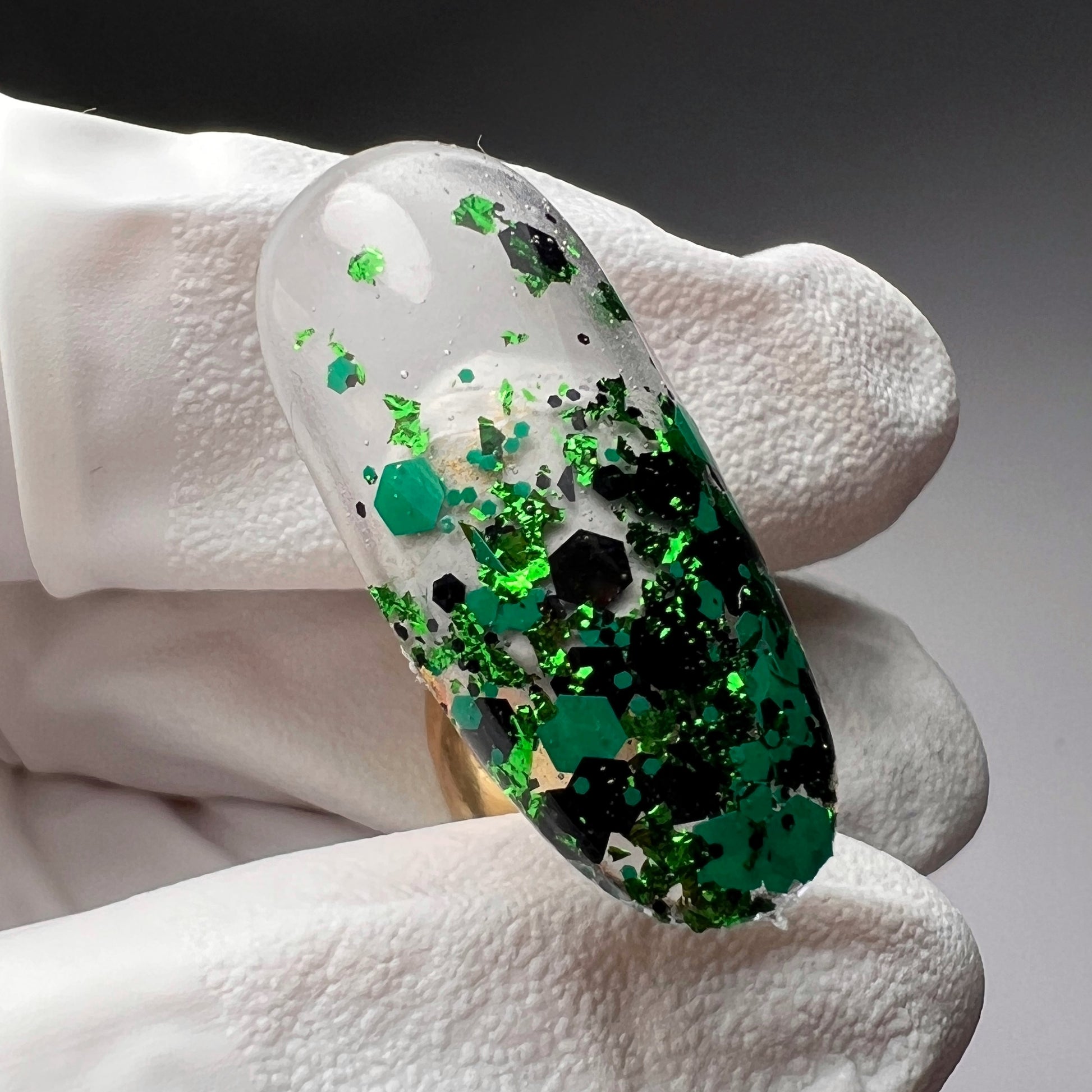 Hand holding decorated nail tip. 