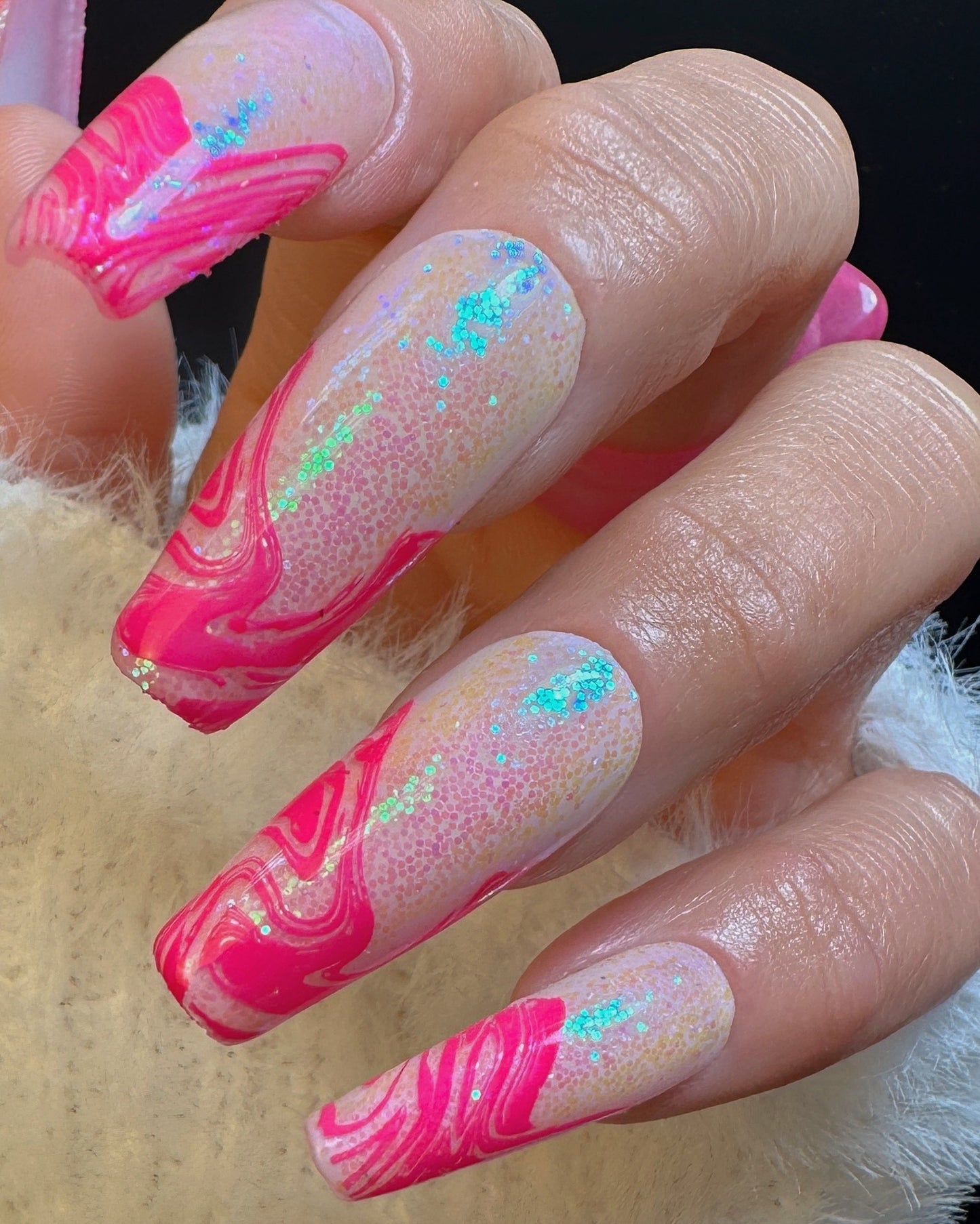 Nails with pink marbled design over iridescent glitter on a neutral nail background