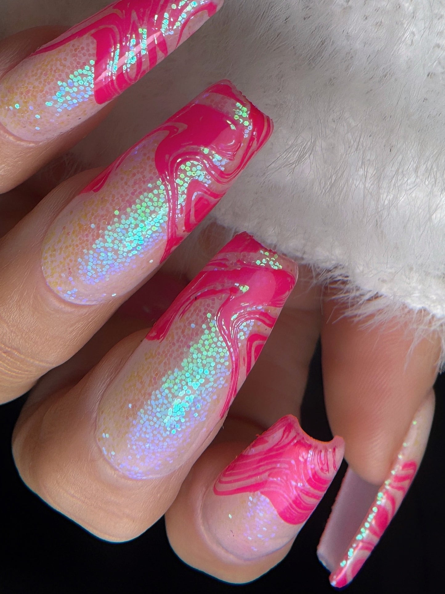 Nails with pink and white marbled design and glitter on a light background