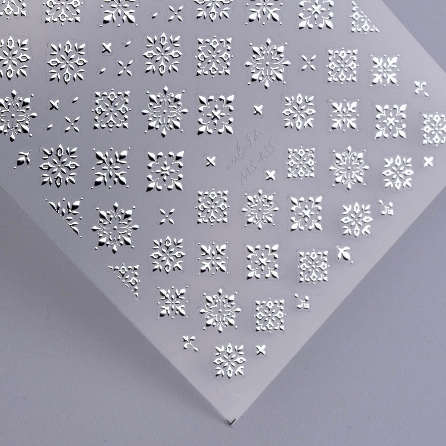 Detail view of nail decal sheet on light background.