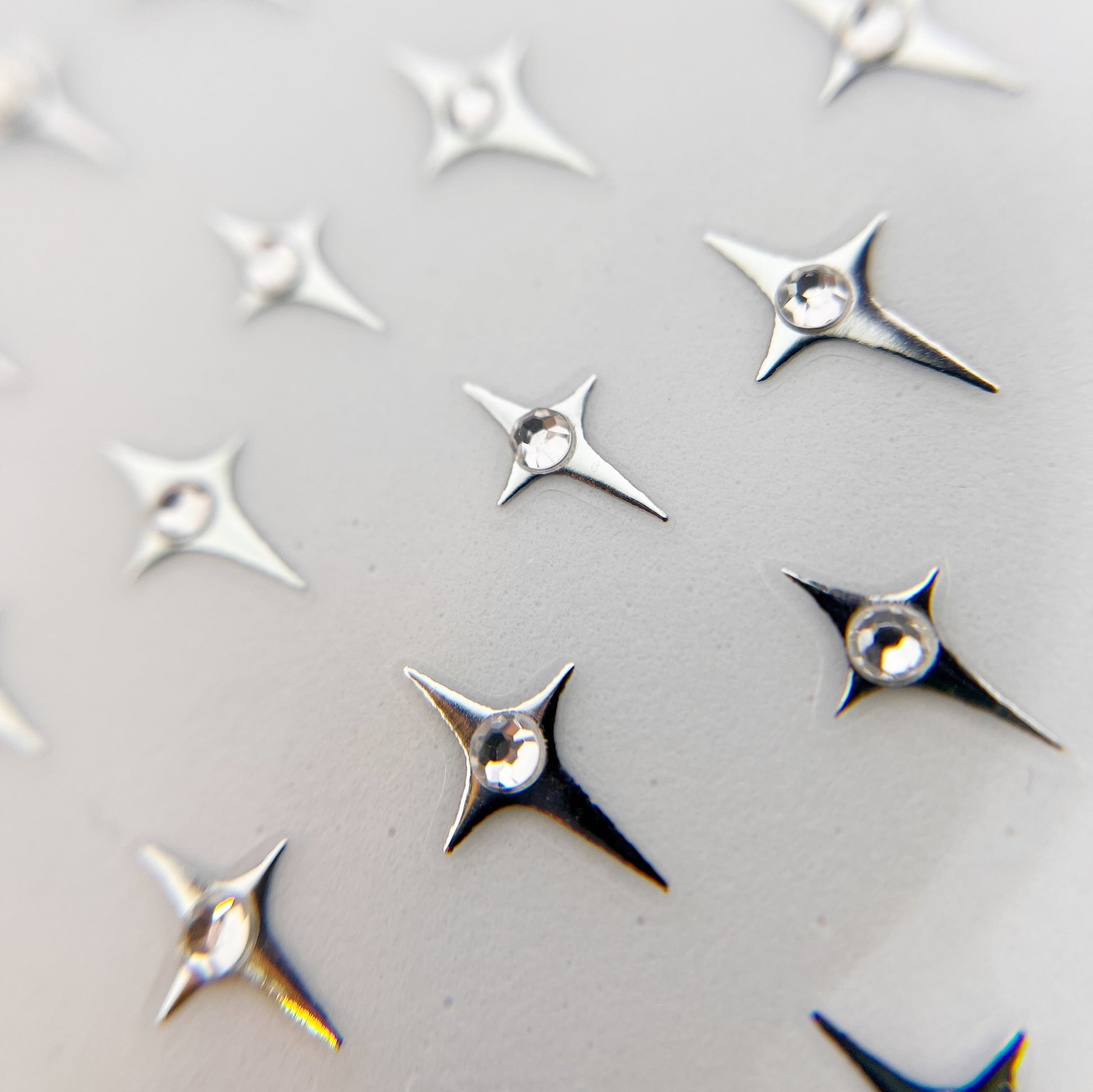 Jewel Star Nail Stickers - Four-Point Stars with Center Rhinestone Detail, Piictured in Silver with clear rhinestone. 
