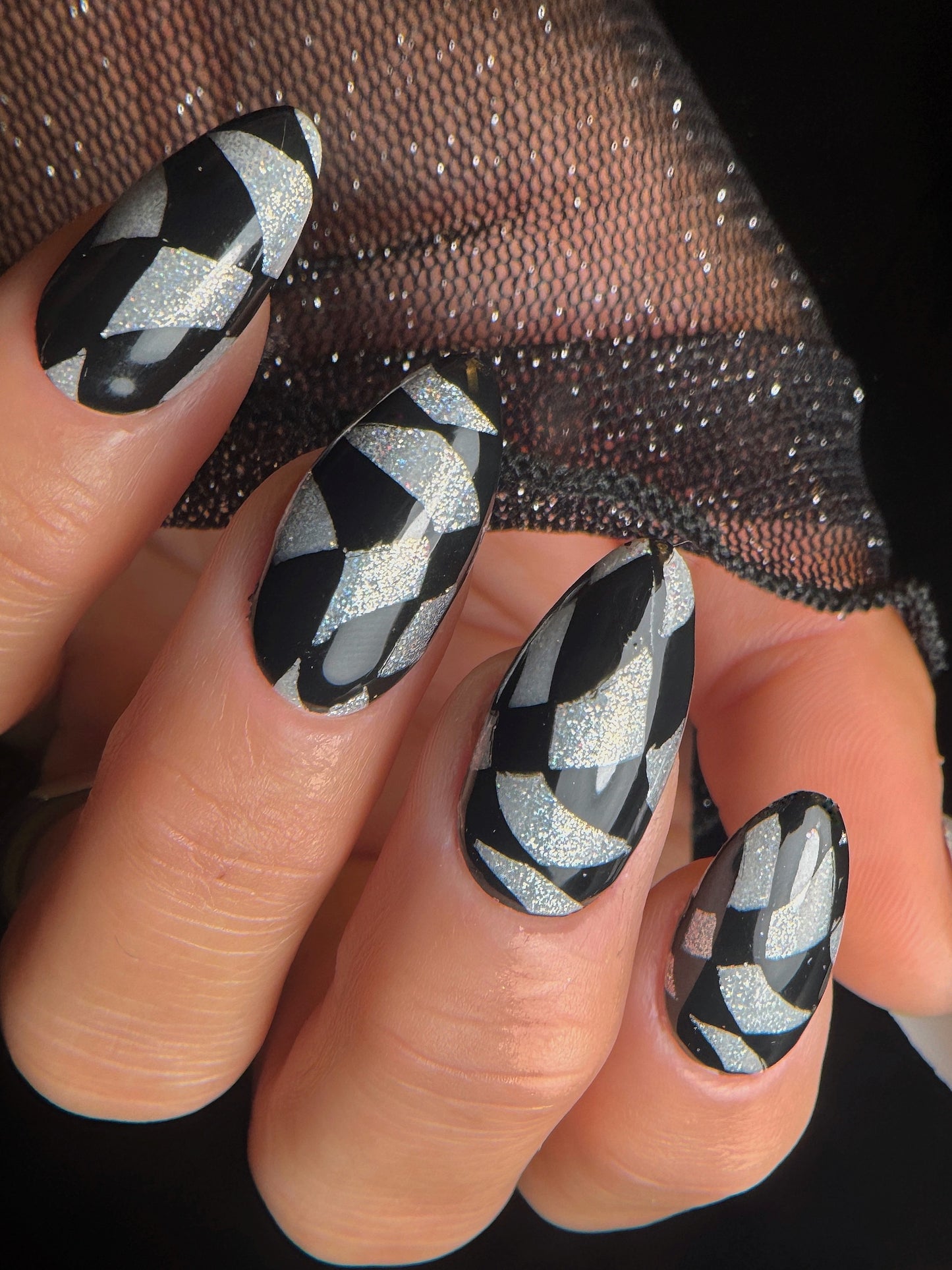Nails with black and silver
 checkered pattern and glittery accents