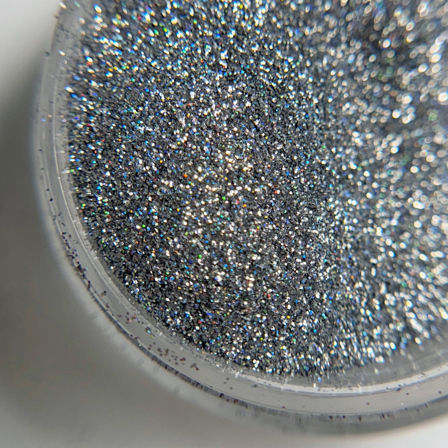 Close up of fine glitter particles in jar on blurred background.