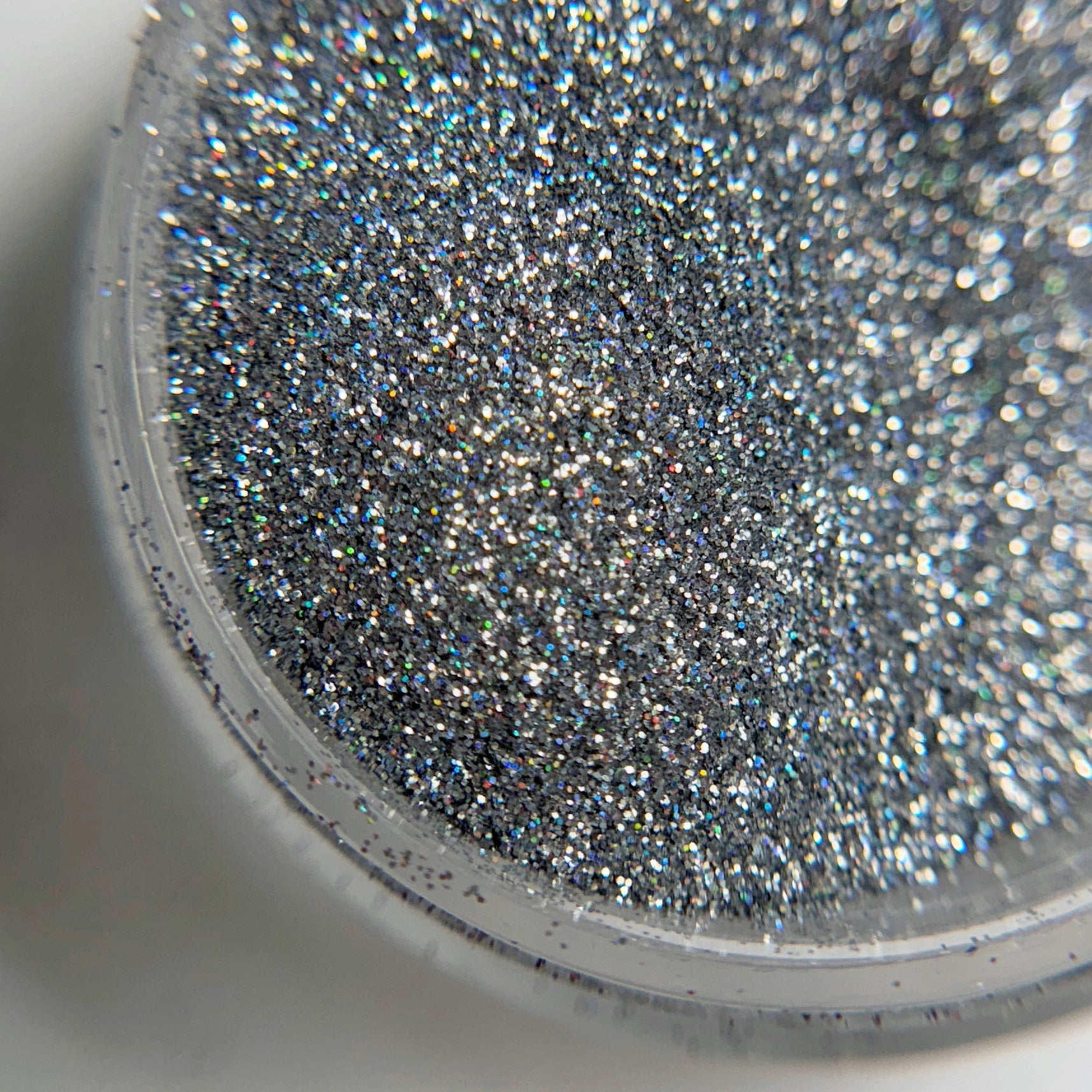 Close up of fine glitter particles in jar on blurred background.
