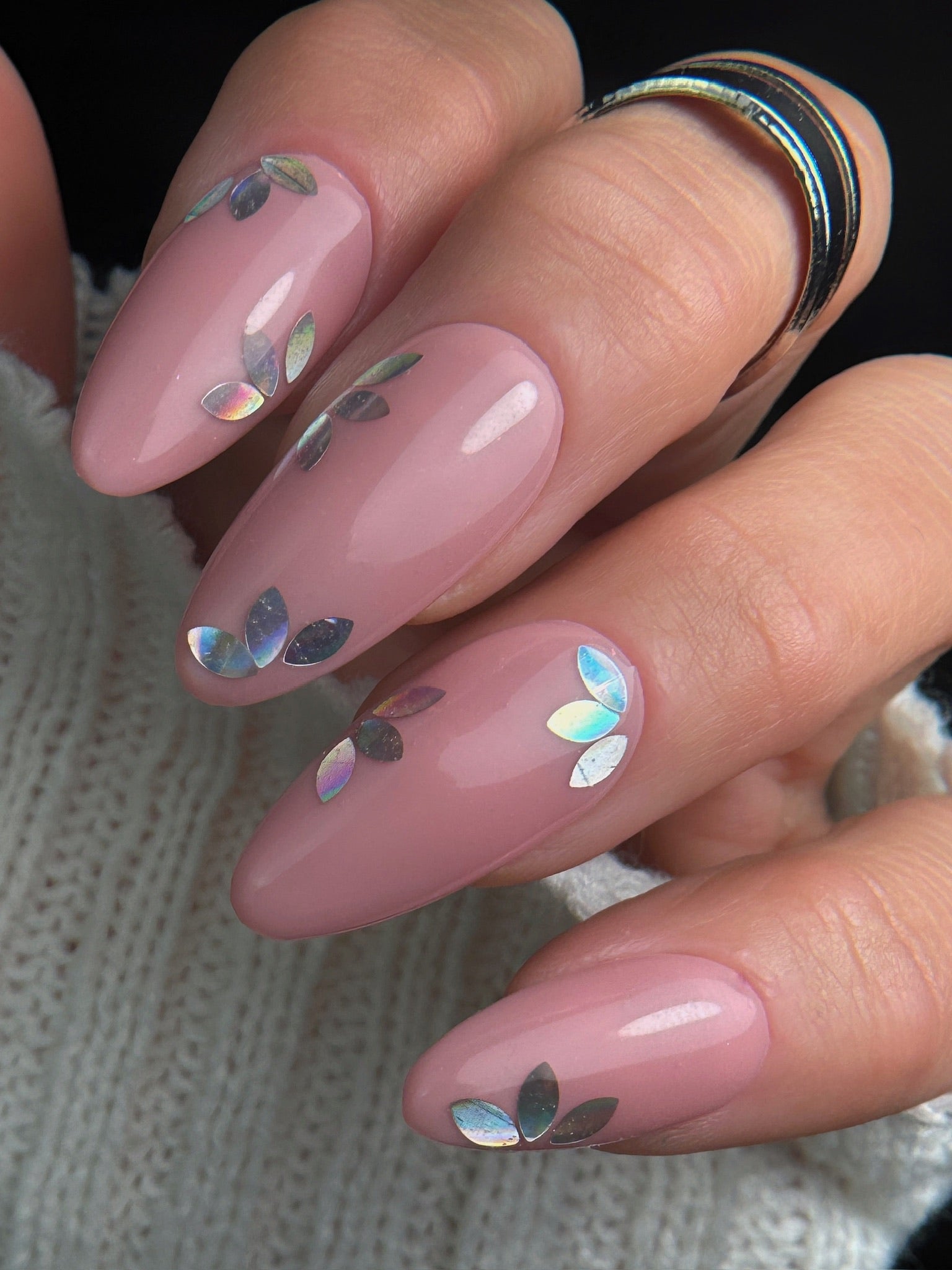 Pink nails with silver floral designs on a textured surface