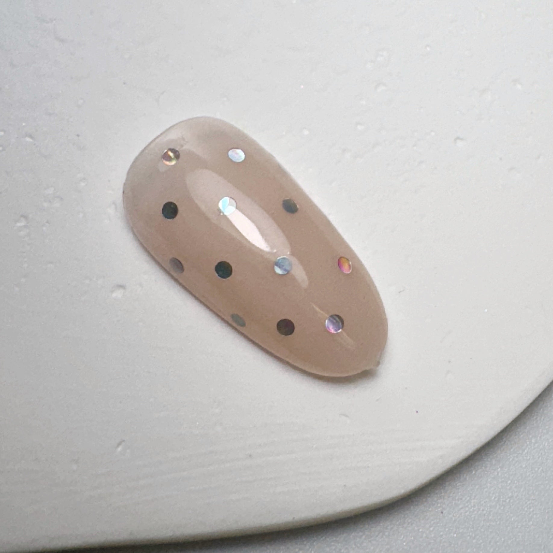 Decorated nail tip on white textured surface.