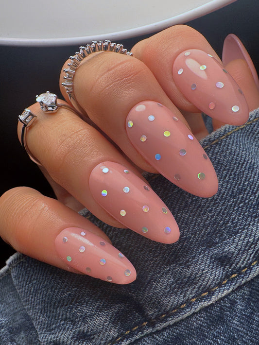 Nails with silver polka dot design and rings on a denim background