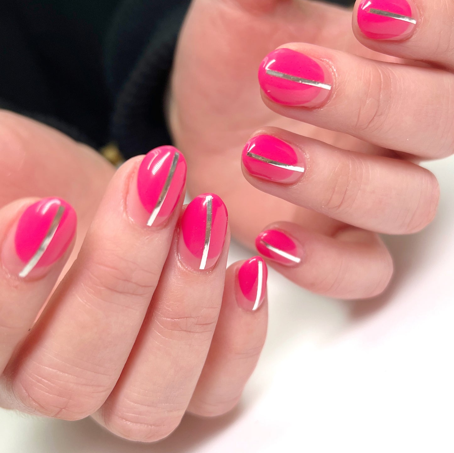 Close-up of hands with pink nails and silver stripes on a white background