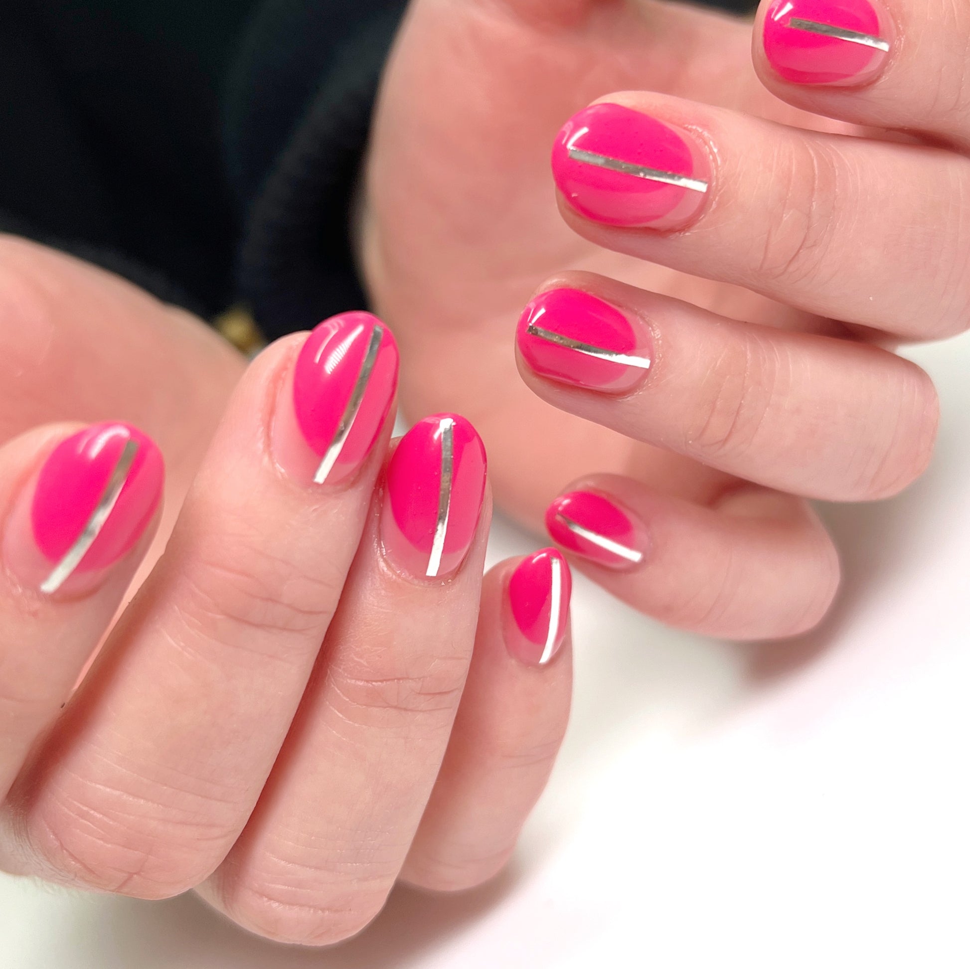 Close-up of hands with pink nails and silver stripes on a white background