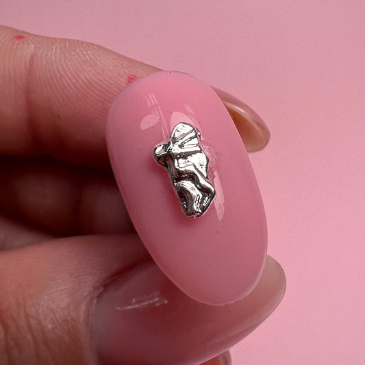 Silver charm on a pink nail against a pink background