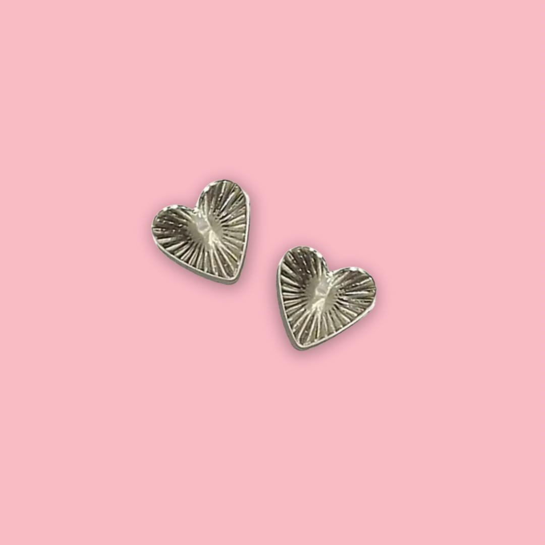 Heart-shaped silver nail charms on a pink background