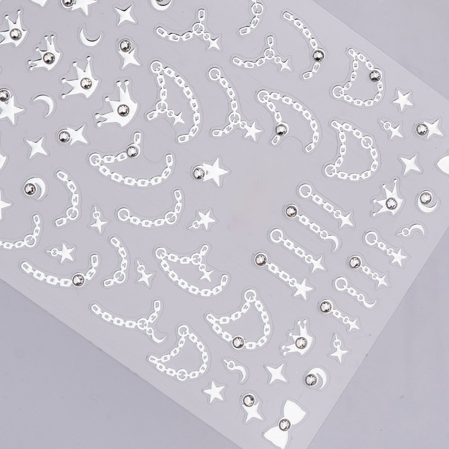 Sheet of decorative stickers with chains, stars, and crowns on a gray background