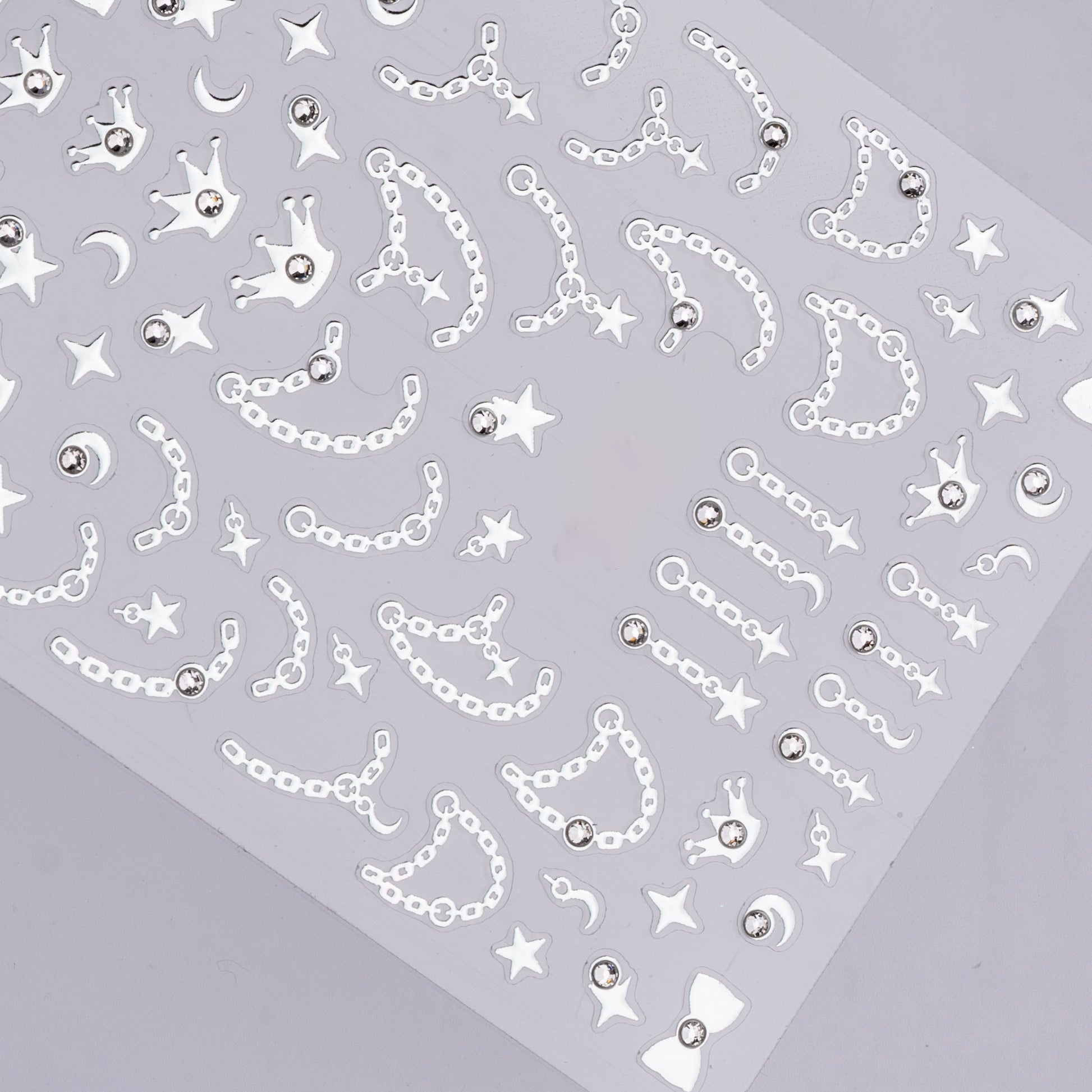 Sheet of decorative stickers with chains, stars, and crowns on a gray background