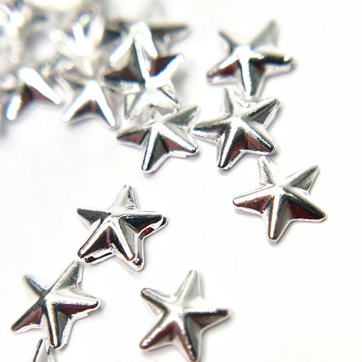 Silver star charms scattered on white background. 