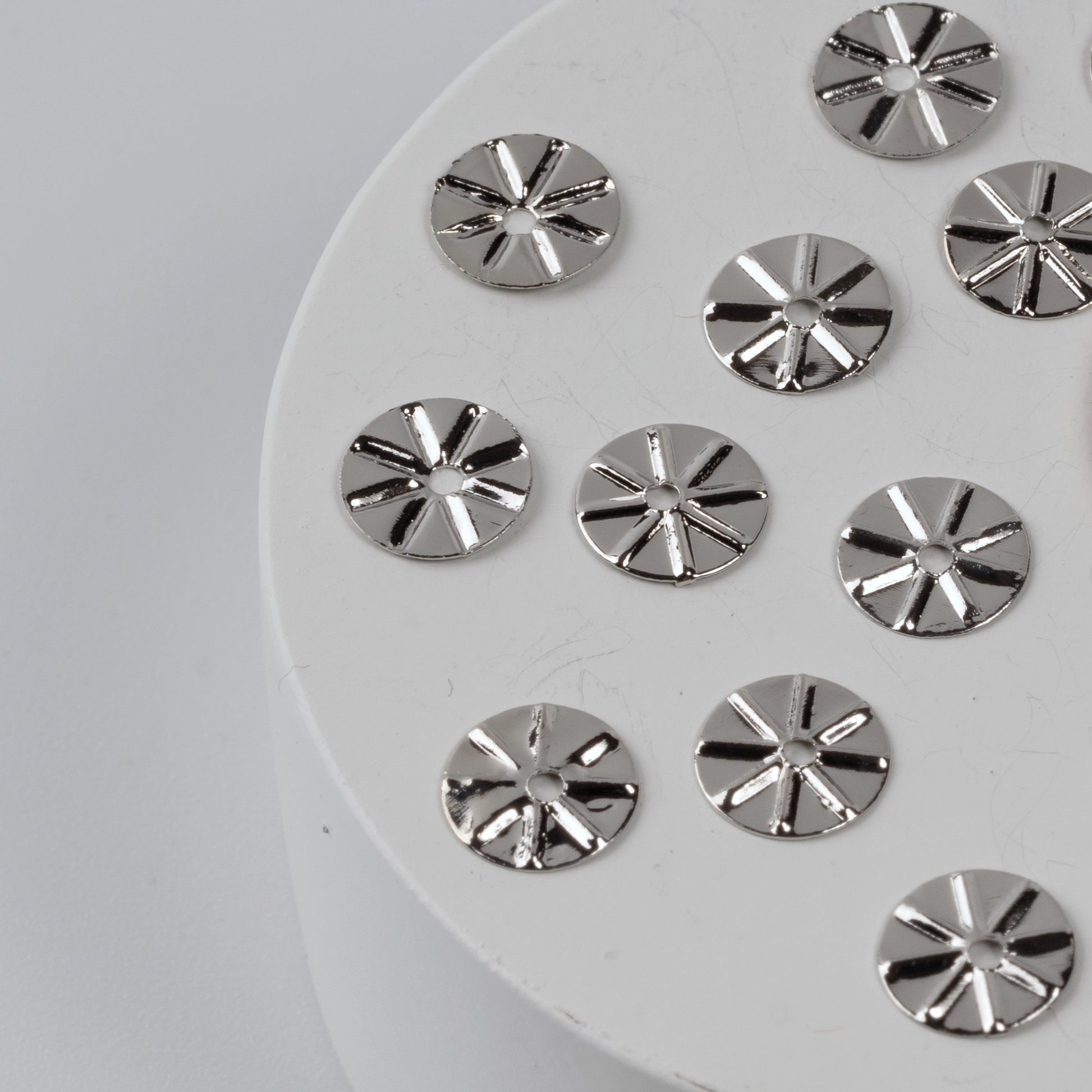 Silver circular embellishments on a white round base