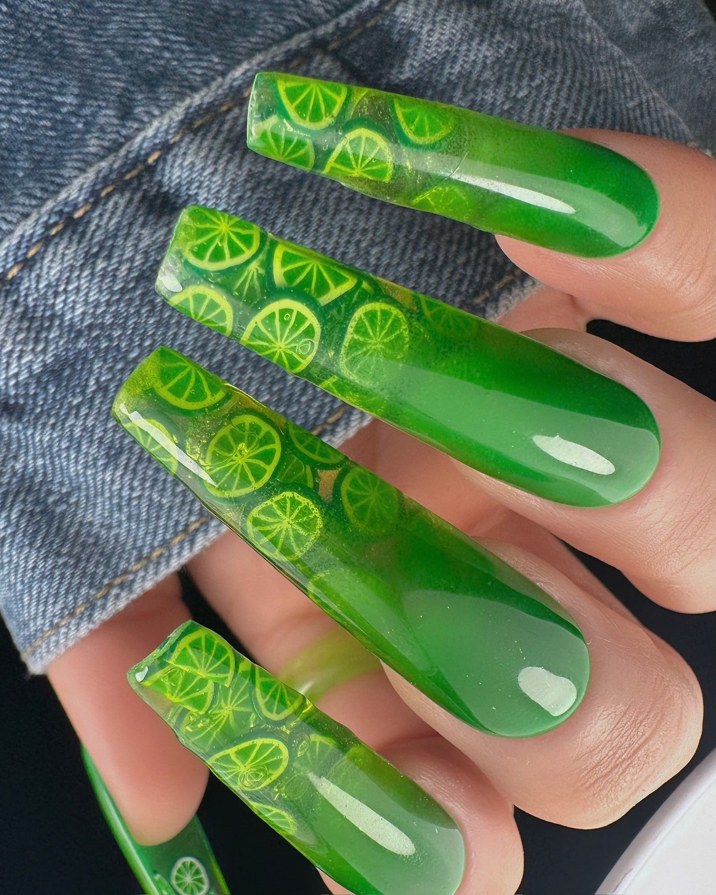 Green nail art with lime pattern on a denim background