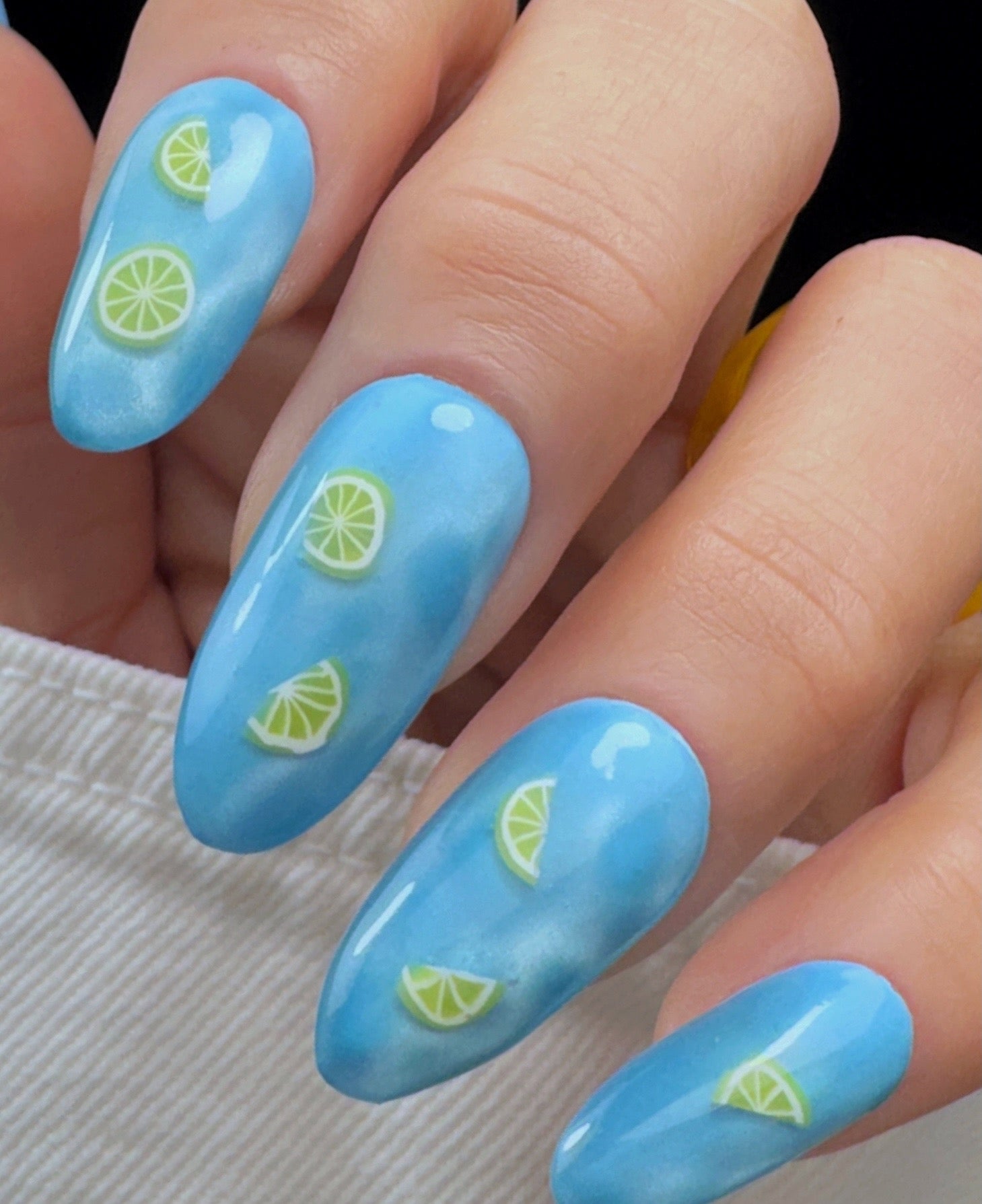 Blue nails with lemon slice design on a hand