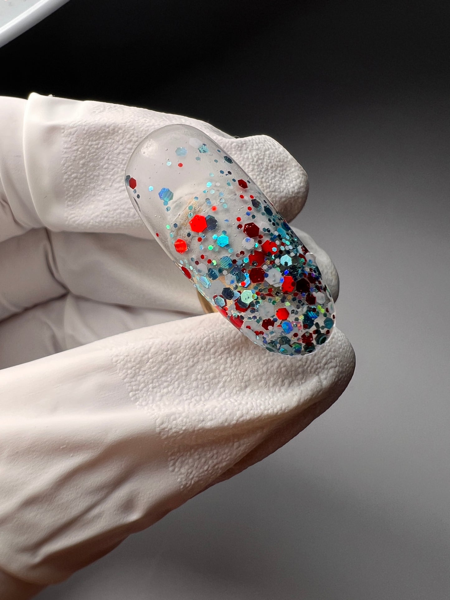 Still of hand holding glitter nail tip. 