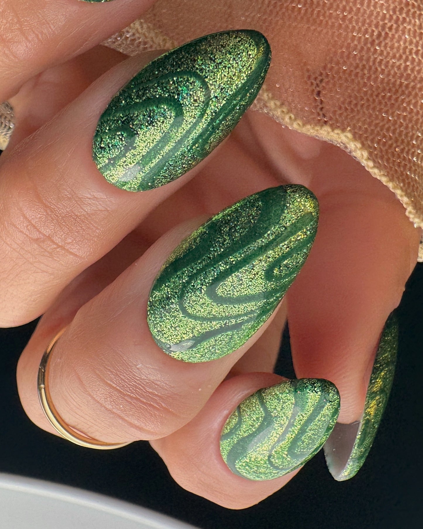 Close-up of a hand with green marbled nail polish on a neutral background