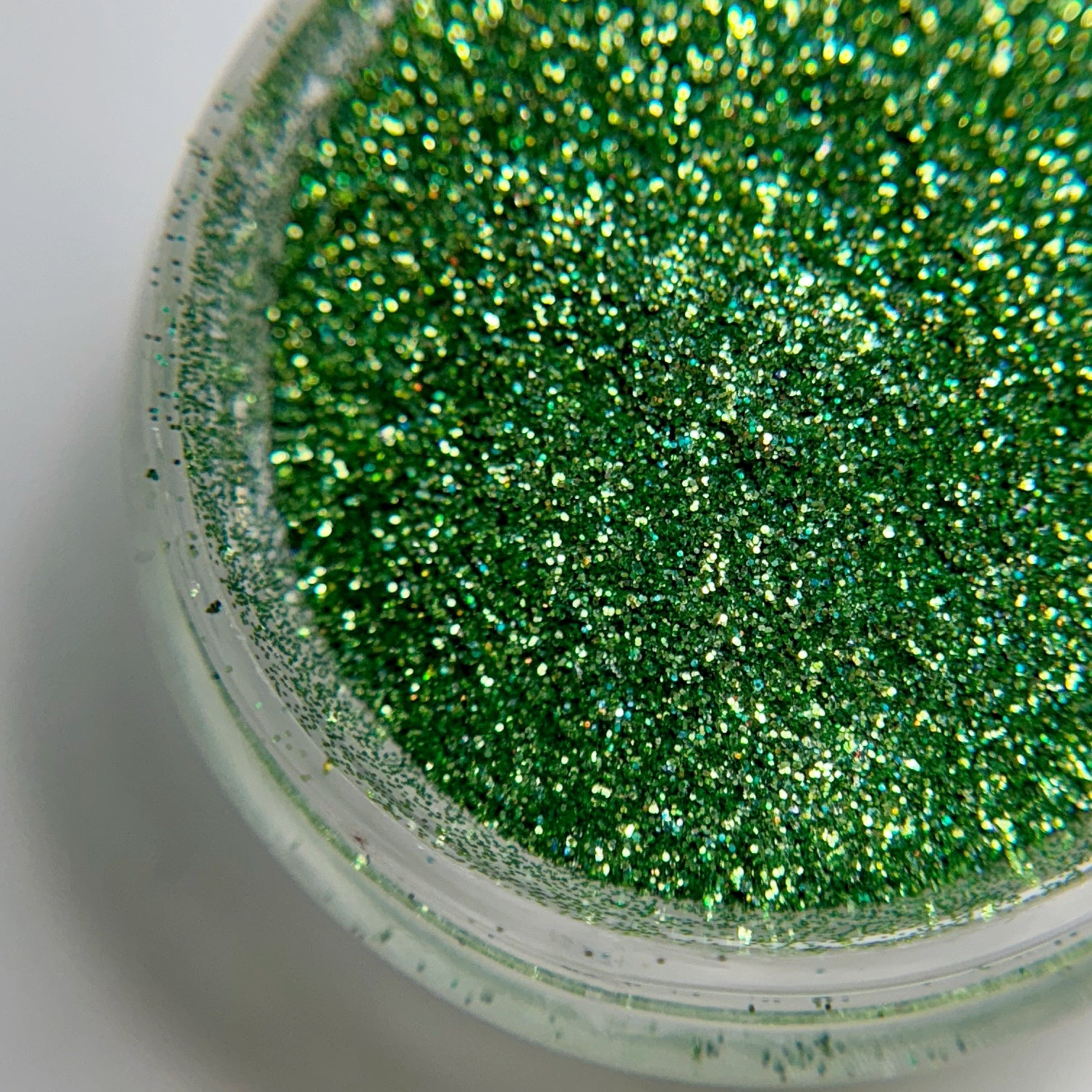 Close up of fine glitter particles in jar on blurred background.