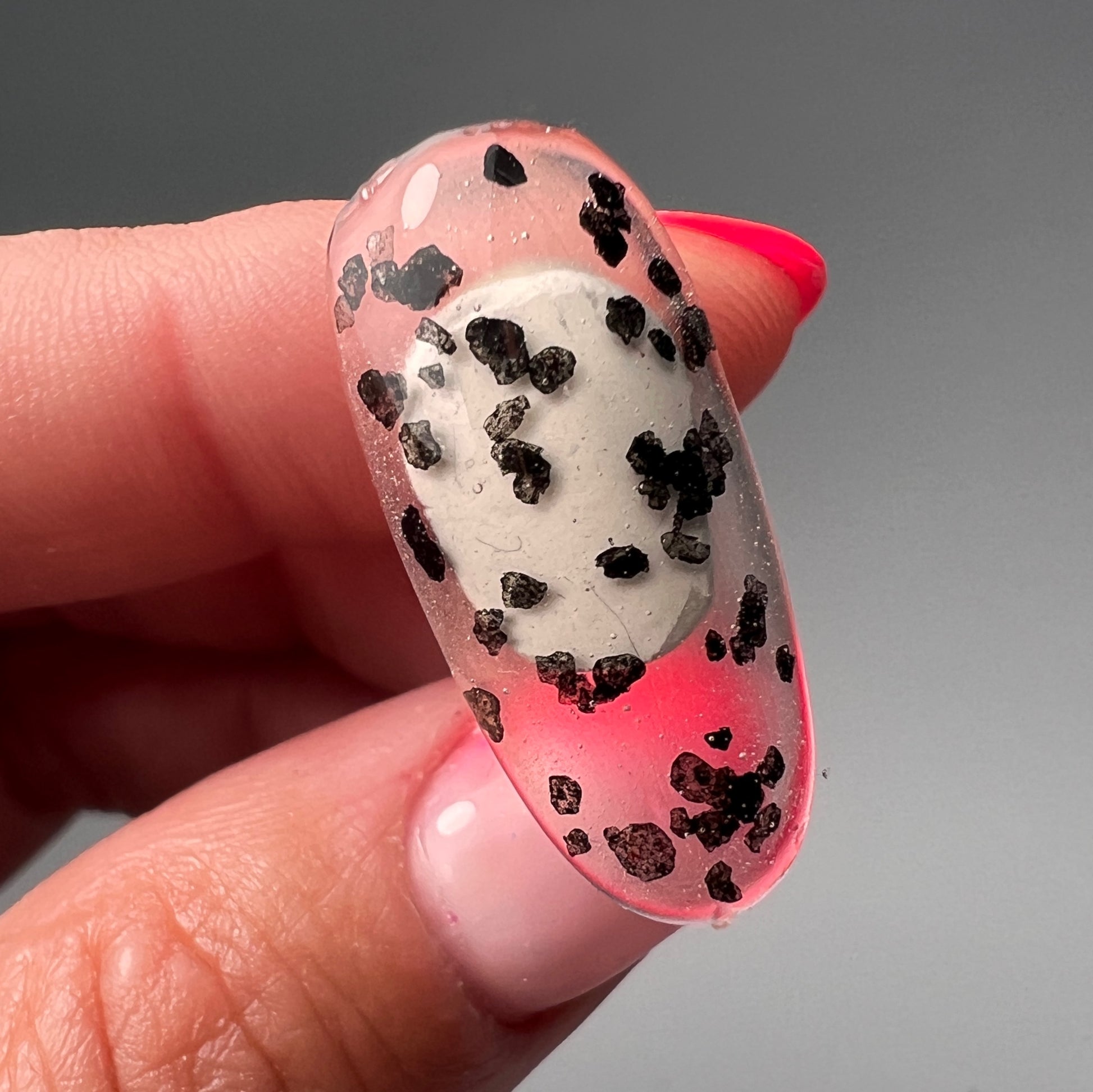 Hand holding decorated nail tip. 