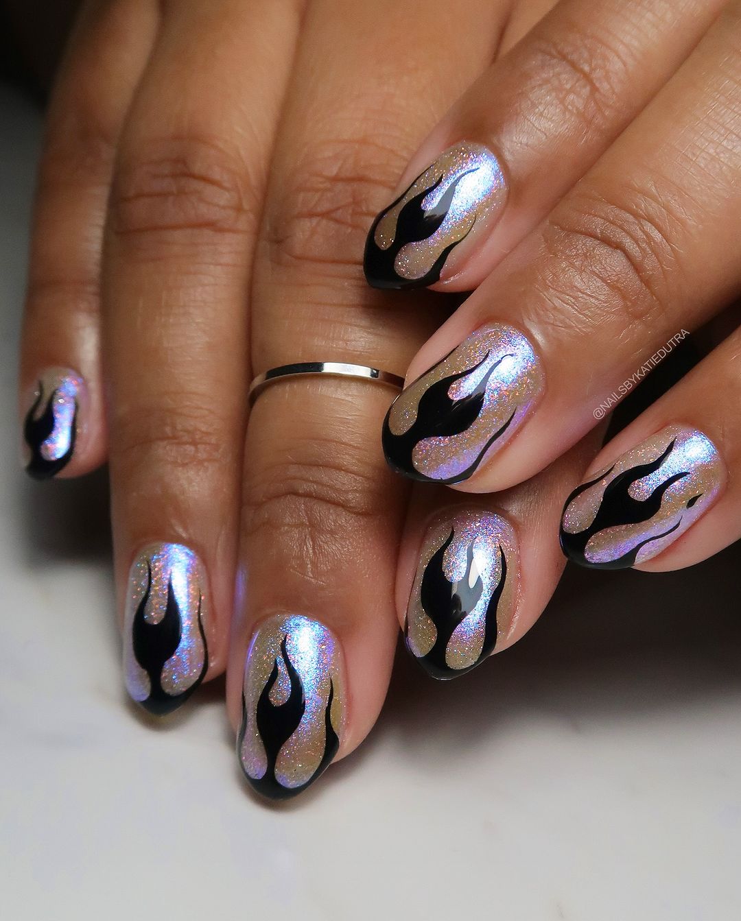 Close up of hands with flame themed nail art on neutral background