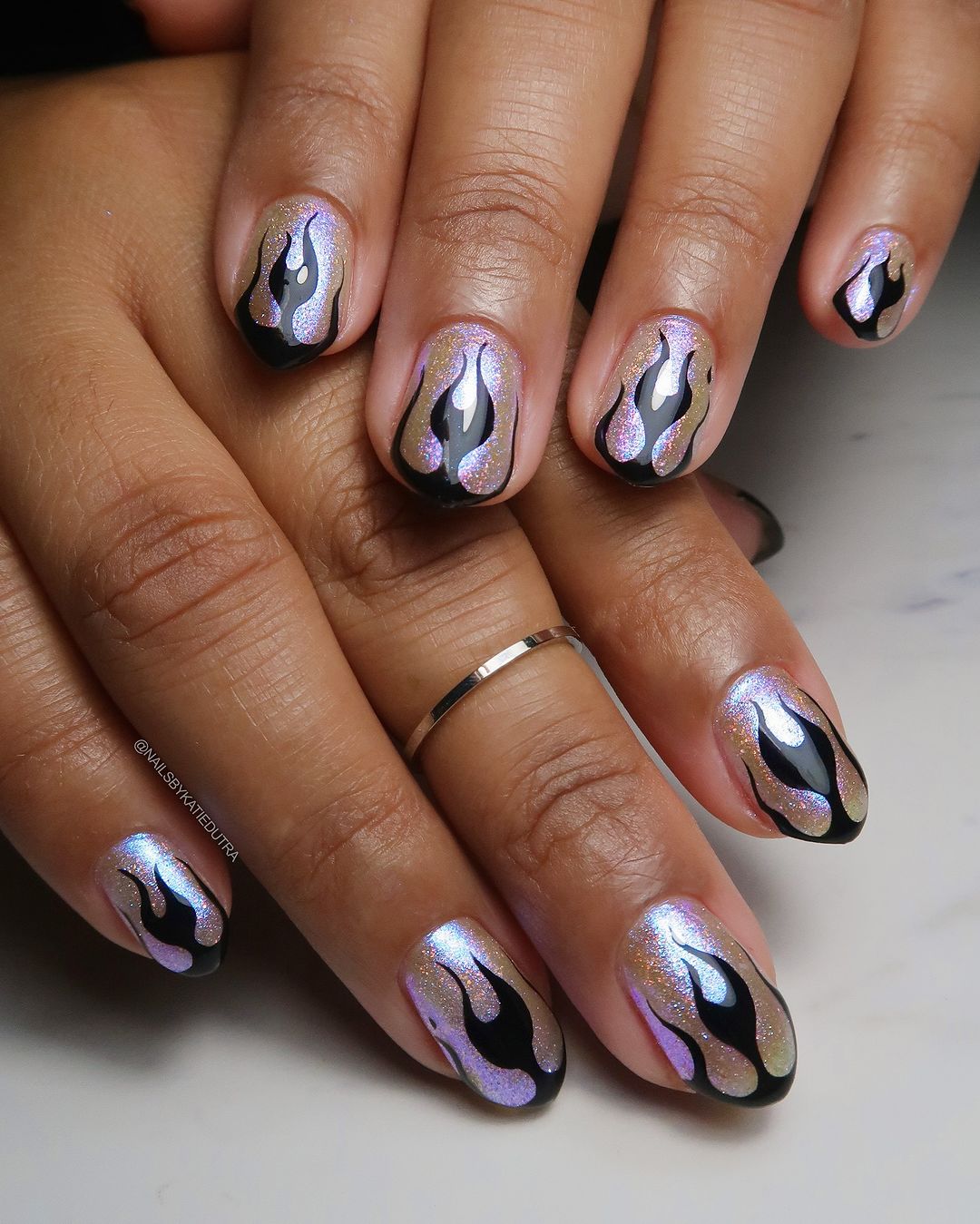 Close-up of a hand with flame-themed nail art on a neutral background