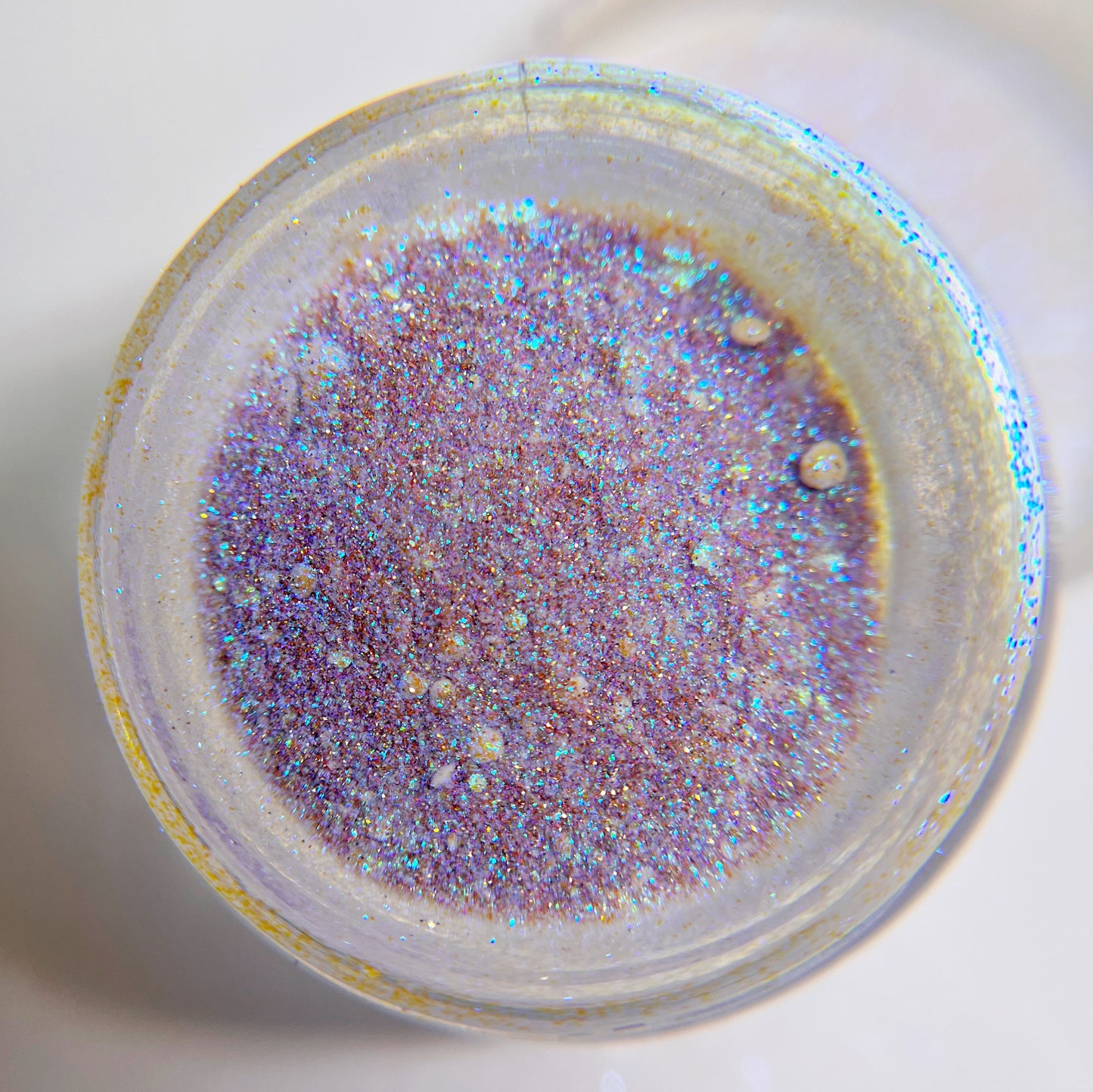 Close up of fine glitter in transparent jar against white background 
