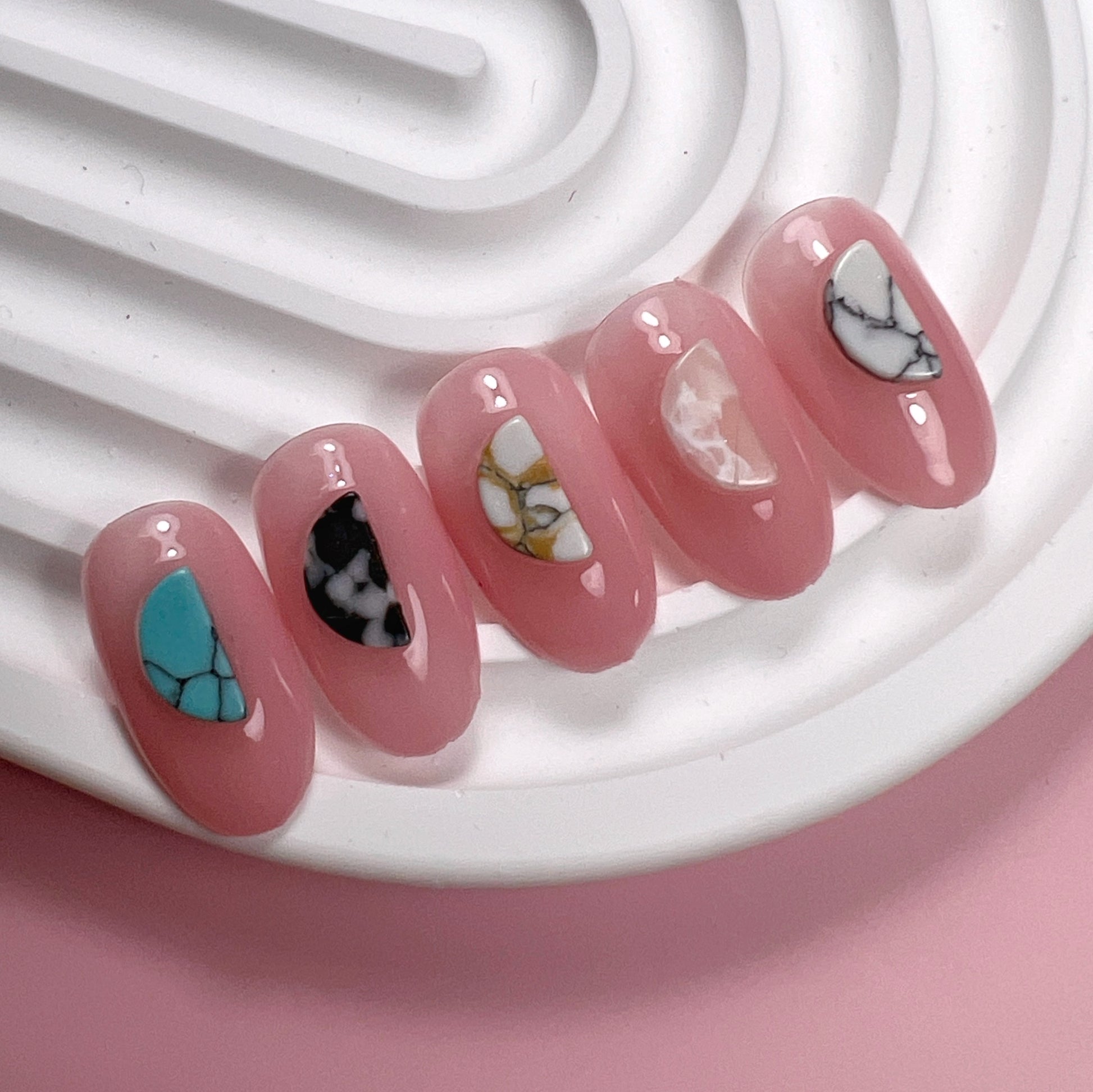 Set of pink nail art designs on a white textured surface and pink background.