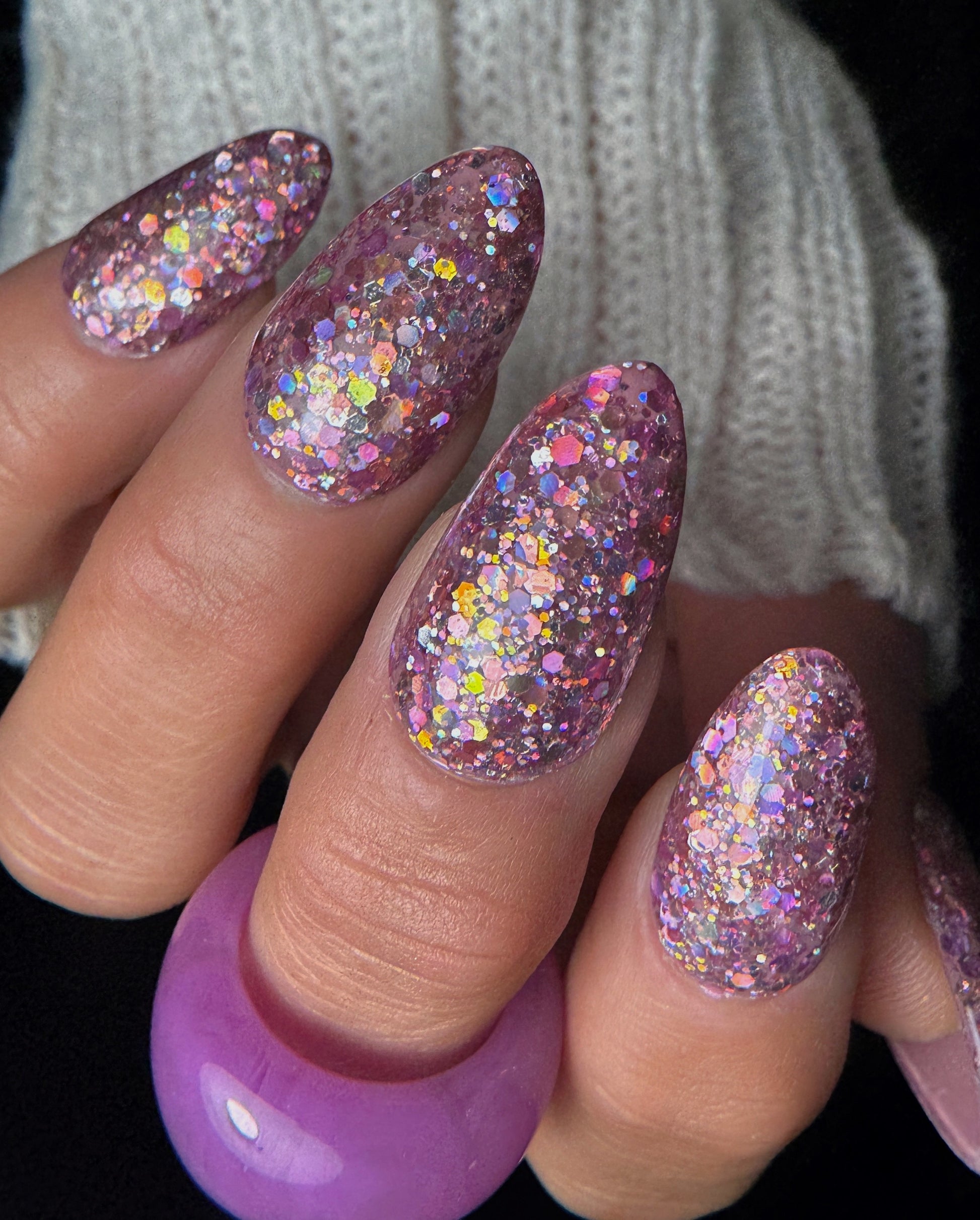 Close-up of a hand with glittery nail design against a blurred background