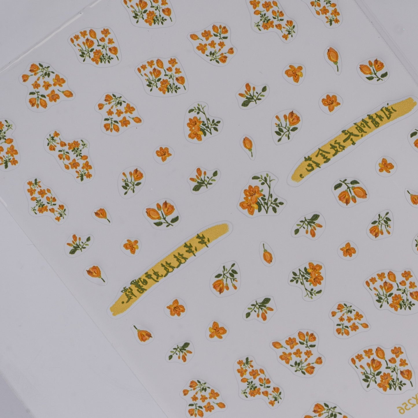 Sheet of orange flower nail stickers on a white background