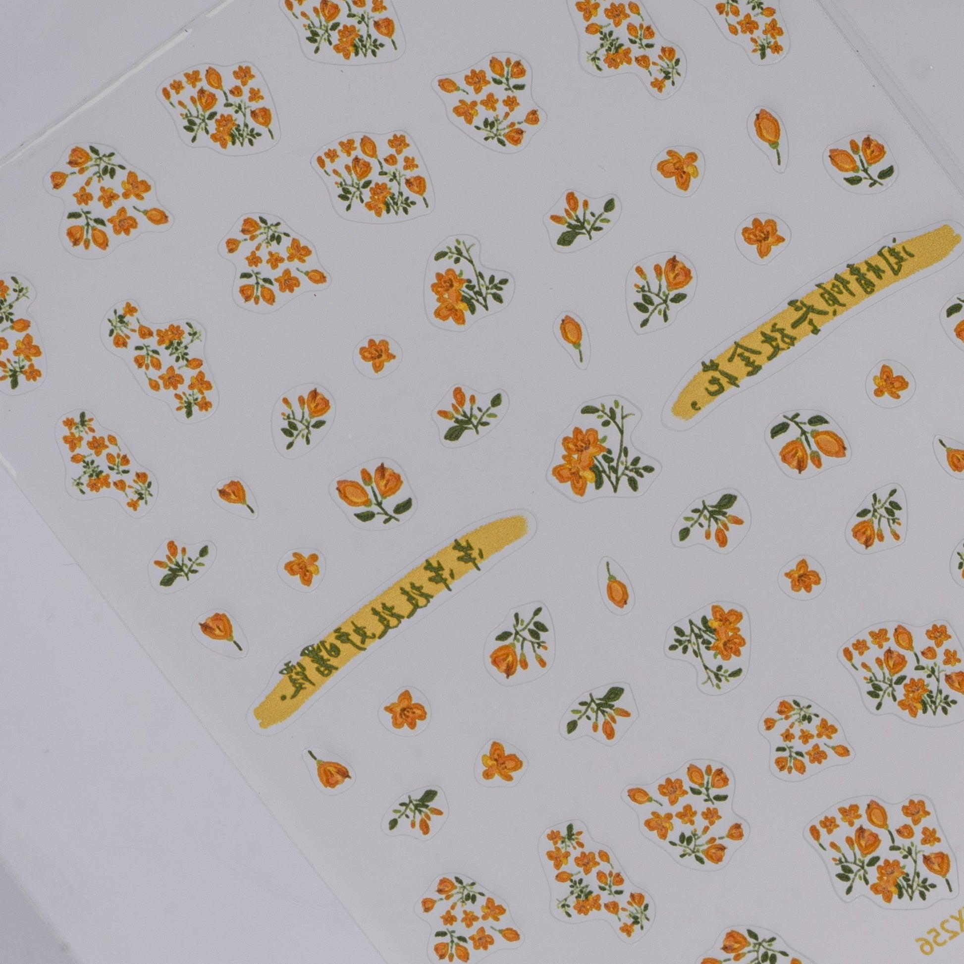 Sheet of orange flower nail stickers on a white background