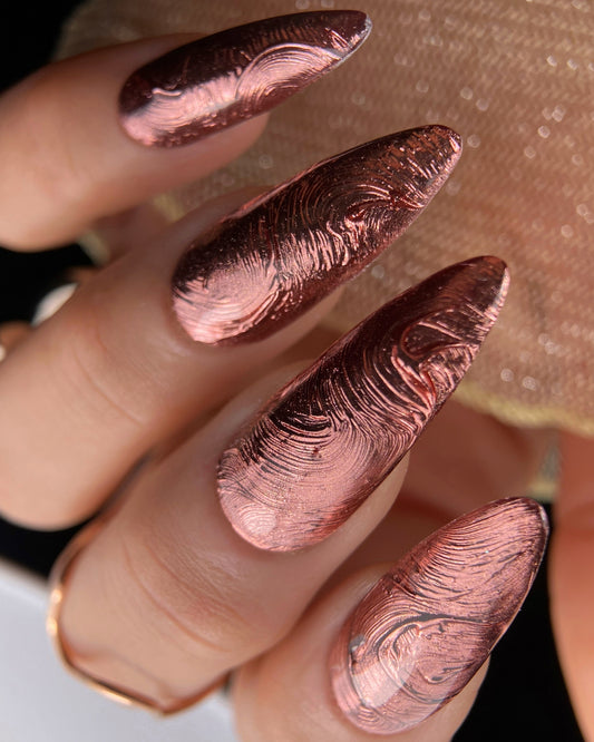 Close-up of a hand with rose bronze metallic nails.