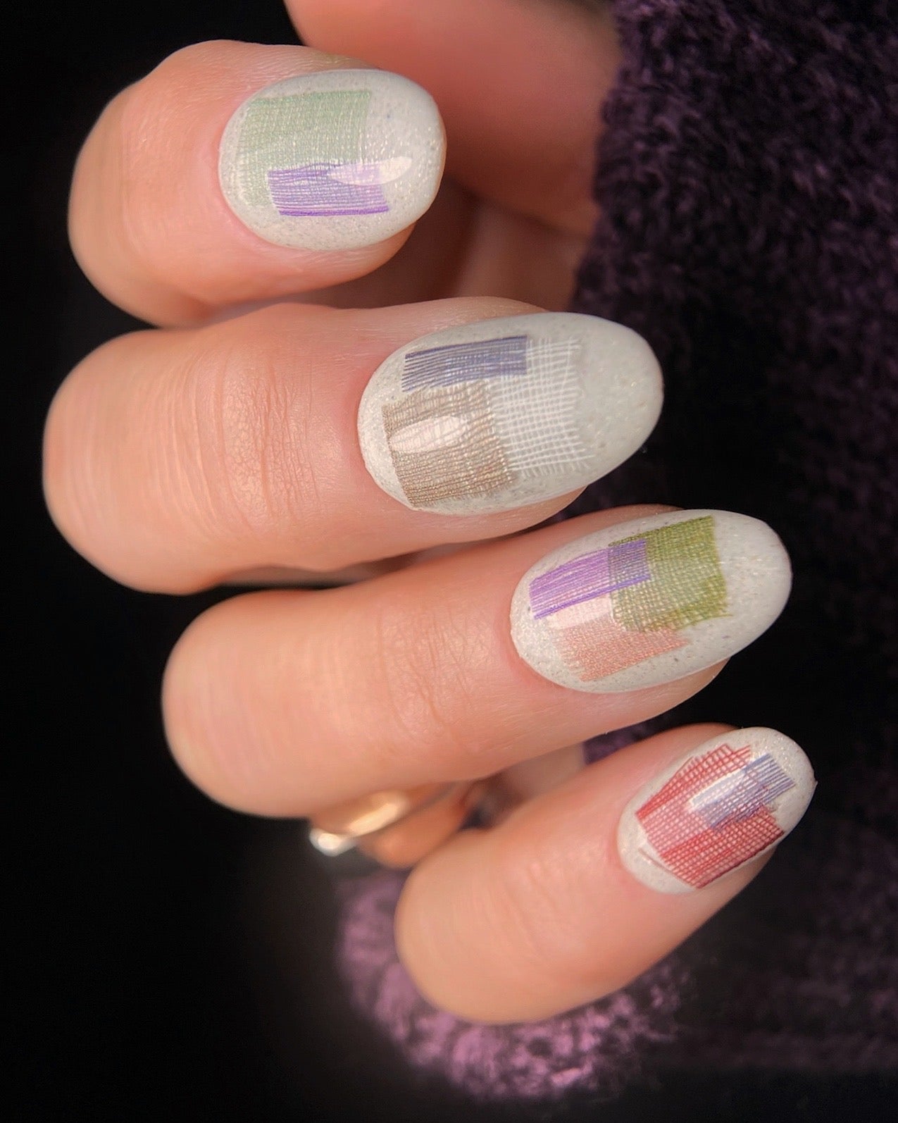 Nails with a checkered pattern in pastel colors held by a hand.